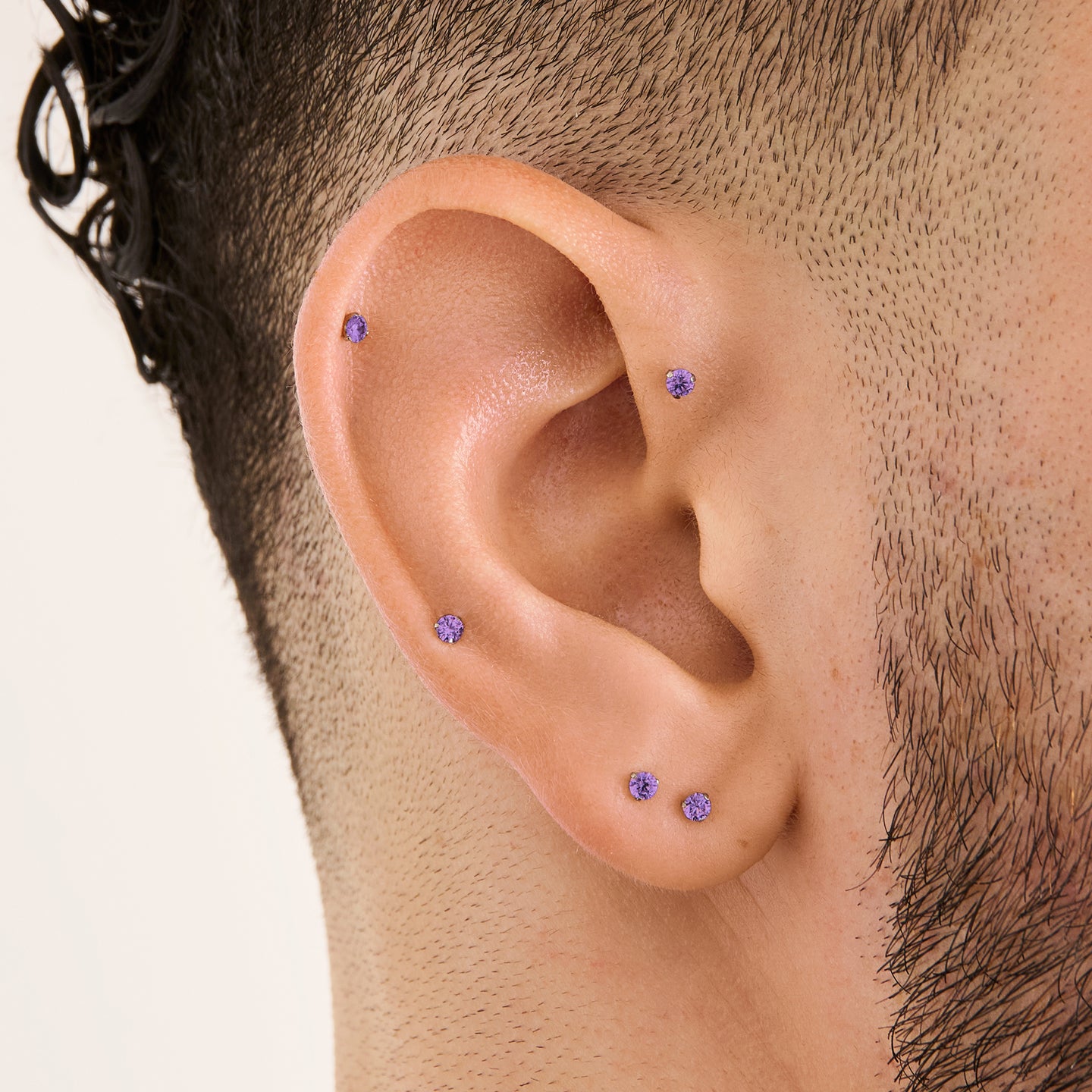 This image is a silver toned titanium flatback stud with an amethyst cz stone on ear. [hover] color:null|amethyst