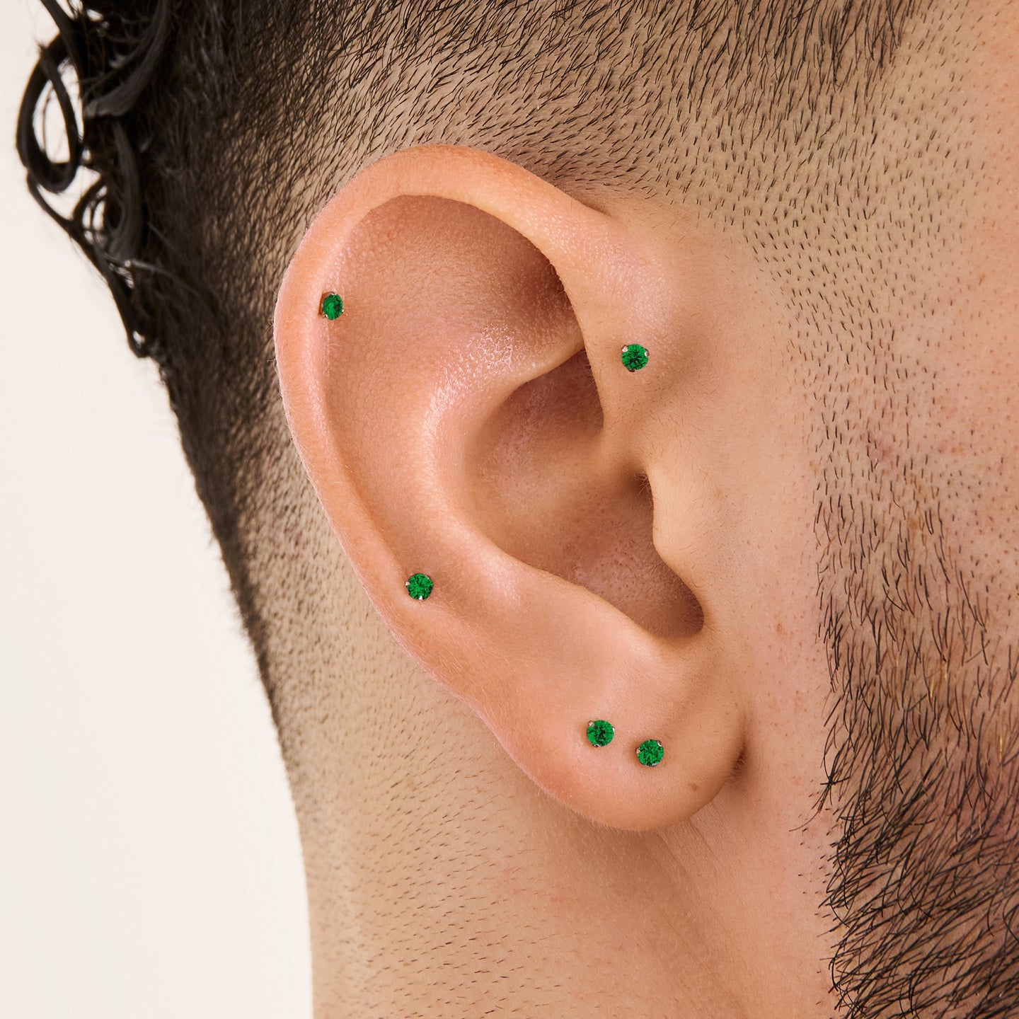 This image is a silver toned titanium flatback stud with an emerald cz stone on ear. [hover] color:null|emerald