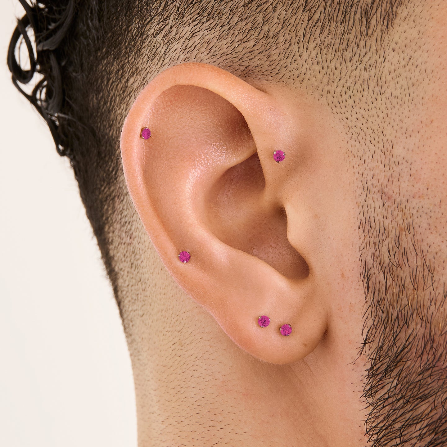 This image is a silver toned titanium flatback stud with a ruby cz stone on ear. [hover] color:null|ruby