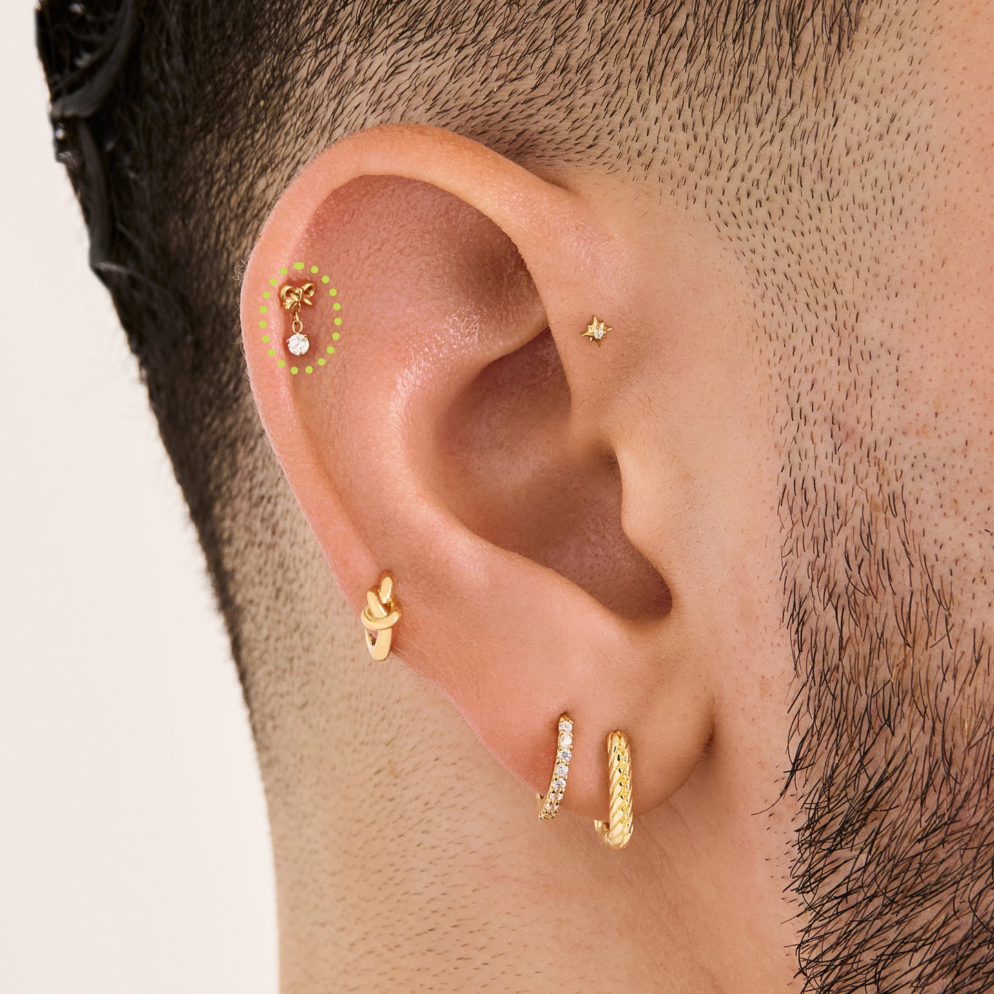 This is an image of a gold-toned flatback stud with a bow that a chain with a CZ dangles from on ear. [hover] color:null|gold/clear