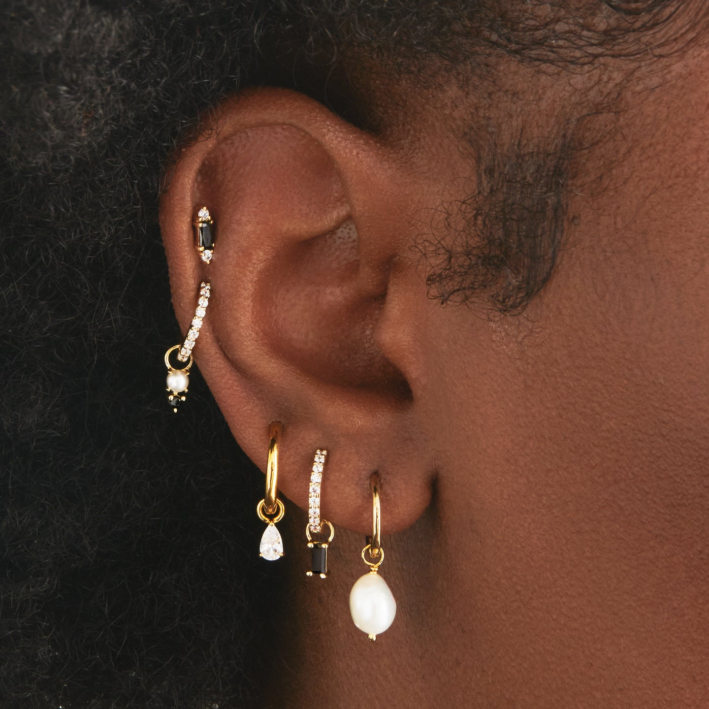 A gold/clear mini pave huggie with black stacked cz pearl charm on ear. [hover] color:null|gold/black