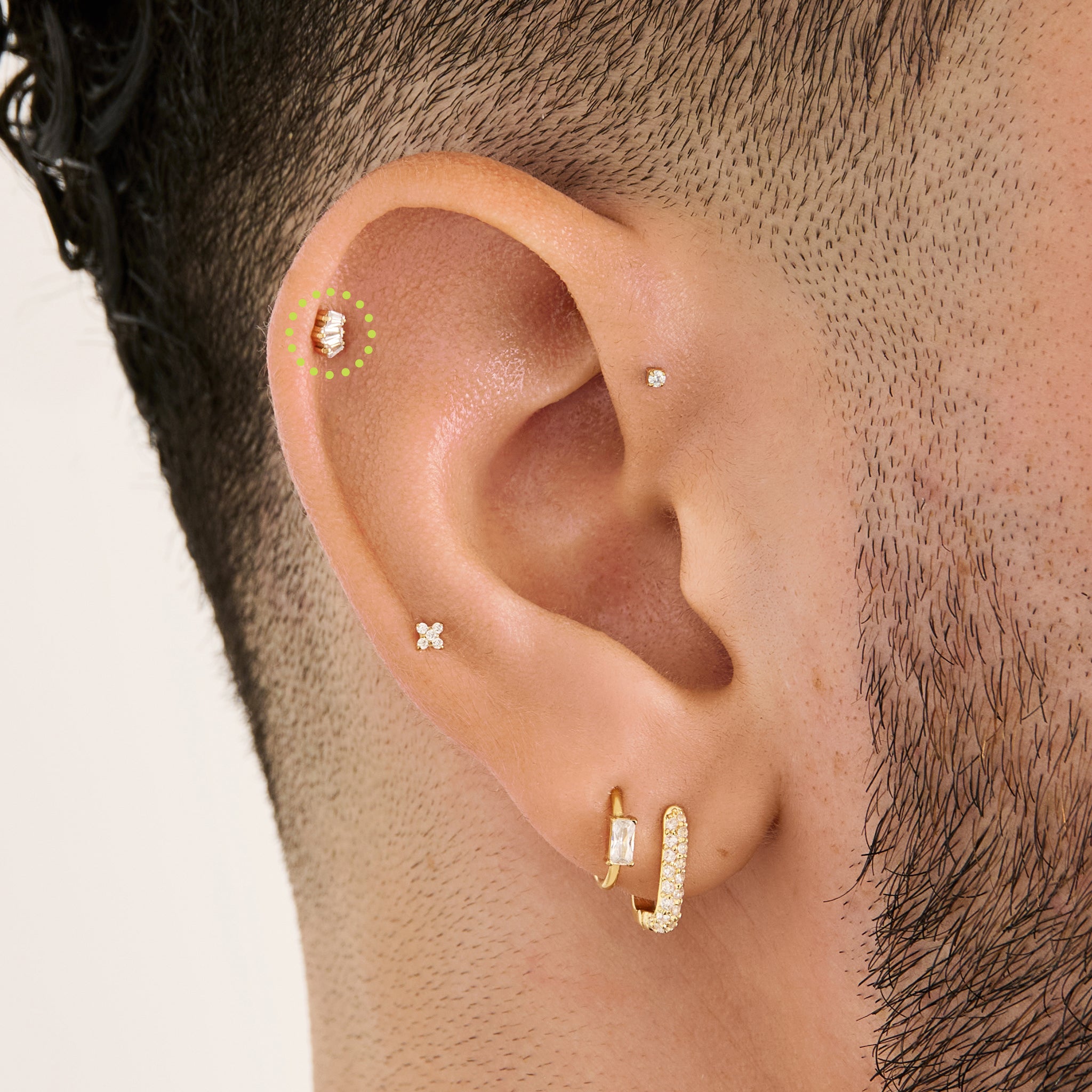 This is an image of a gold-toned flatback stud that is micro baguette shaped CZ's in a crown shape on ear. [hover] color:null|gold/clear