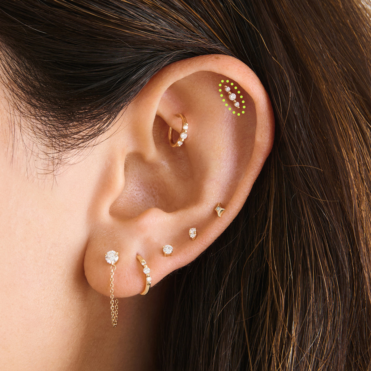 This image is a 14K gold flatback stud that features 3 round diamonds with alternating 14K gold spheres circled on an ear.