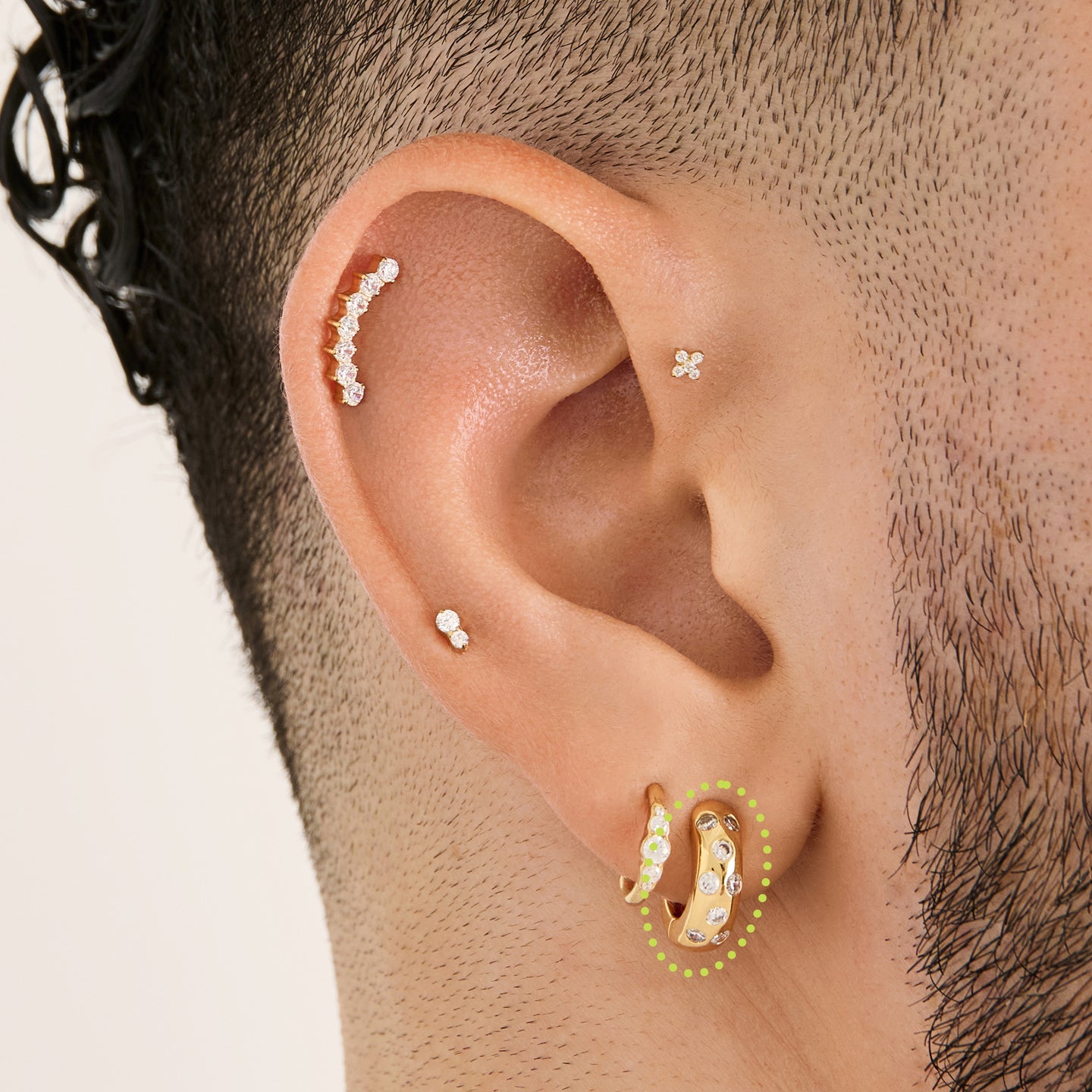 This is an image of a gold-toned huggie that is chunky with CZs encrusted in it on ear. [hover] color:null|gold/clear