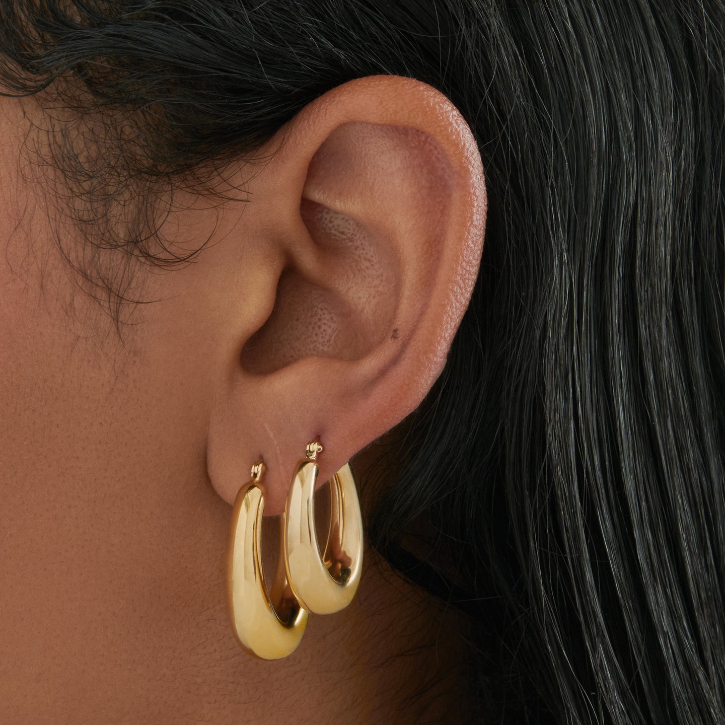 This is a gold, medium-sized, oval crescent shaped hoop. [hover] color:null|gold