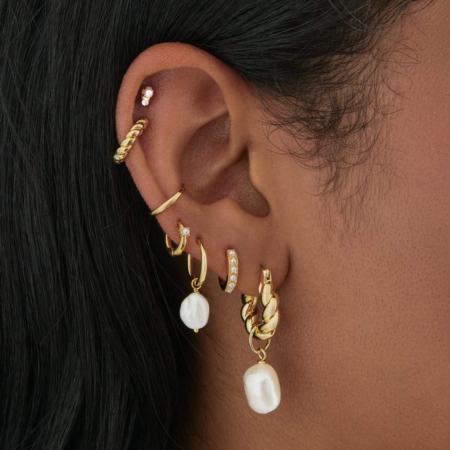 This is an image of a gold small french twist hoop with an oversized baroque pearl charm on it on ear. [hover] color:null|gold/pearl