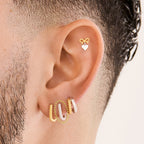This is an image of a silver-toned, square shaped huggie that has twists throughout it on ear. [hover] color:null|silver