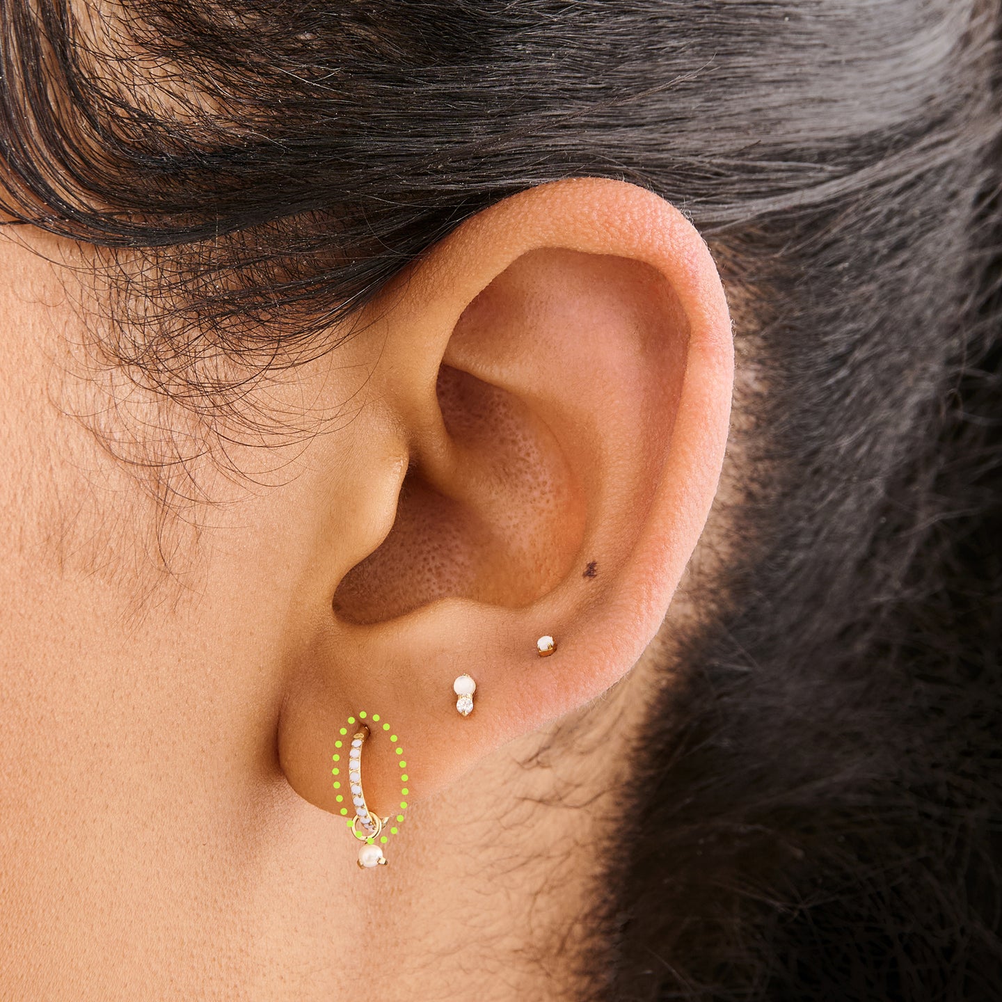 This is an image of a gold-toned titanium clicker with pearl cz stones on ear. [hover] color:null|pearl