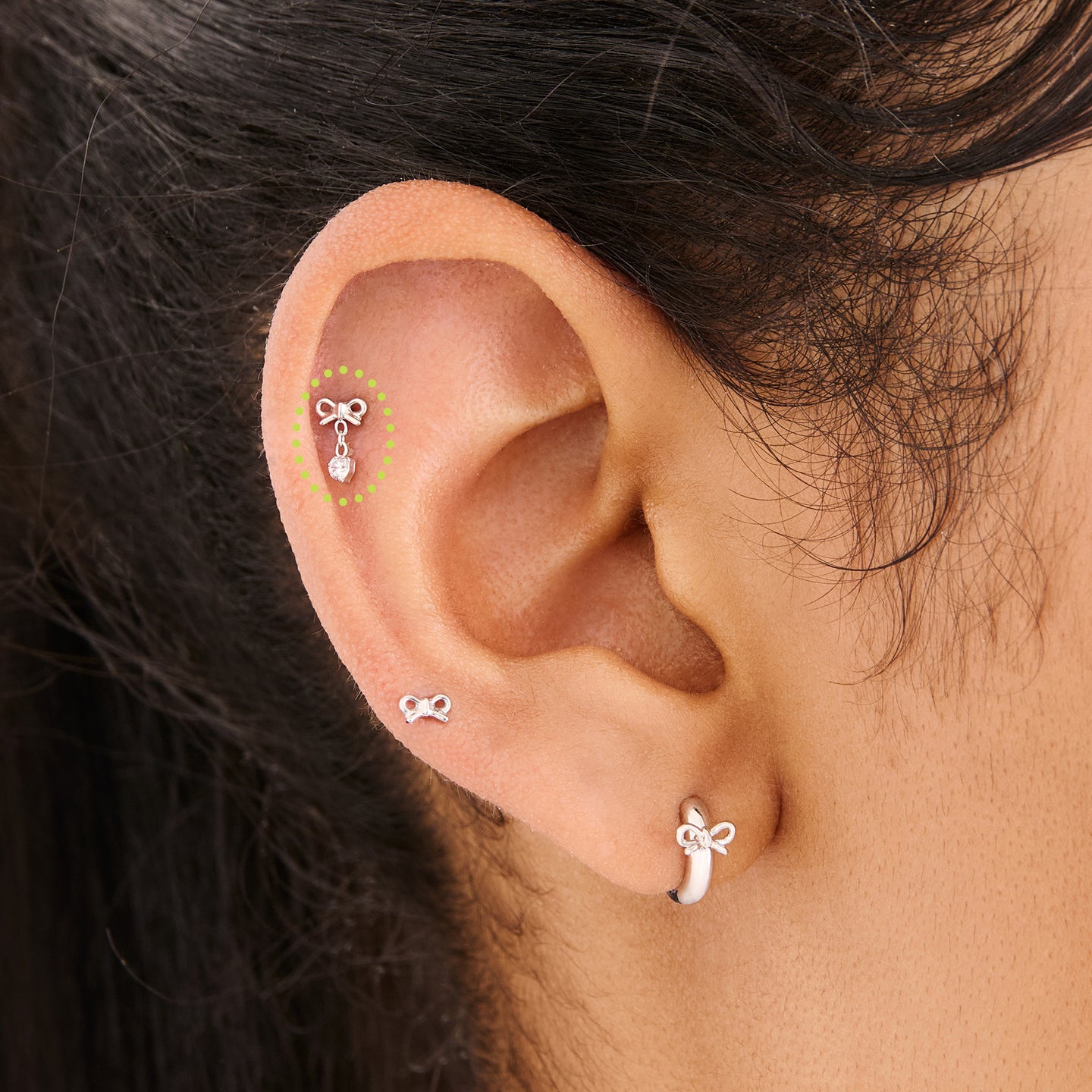 This is an image of a silver-toned flatback stud with a bow that a chain with a CZ dangles from on ear. [hover] color:null|silver/clear