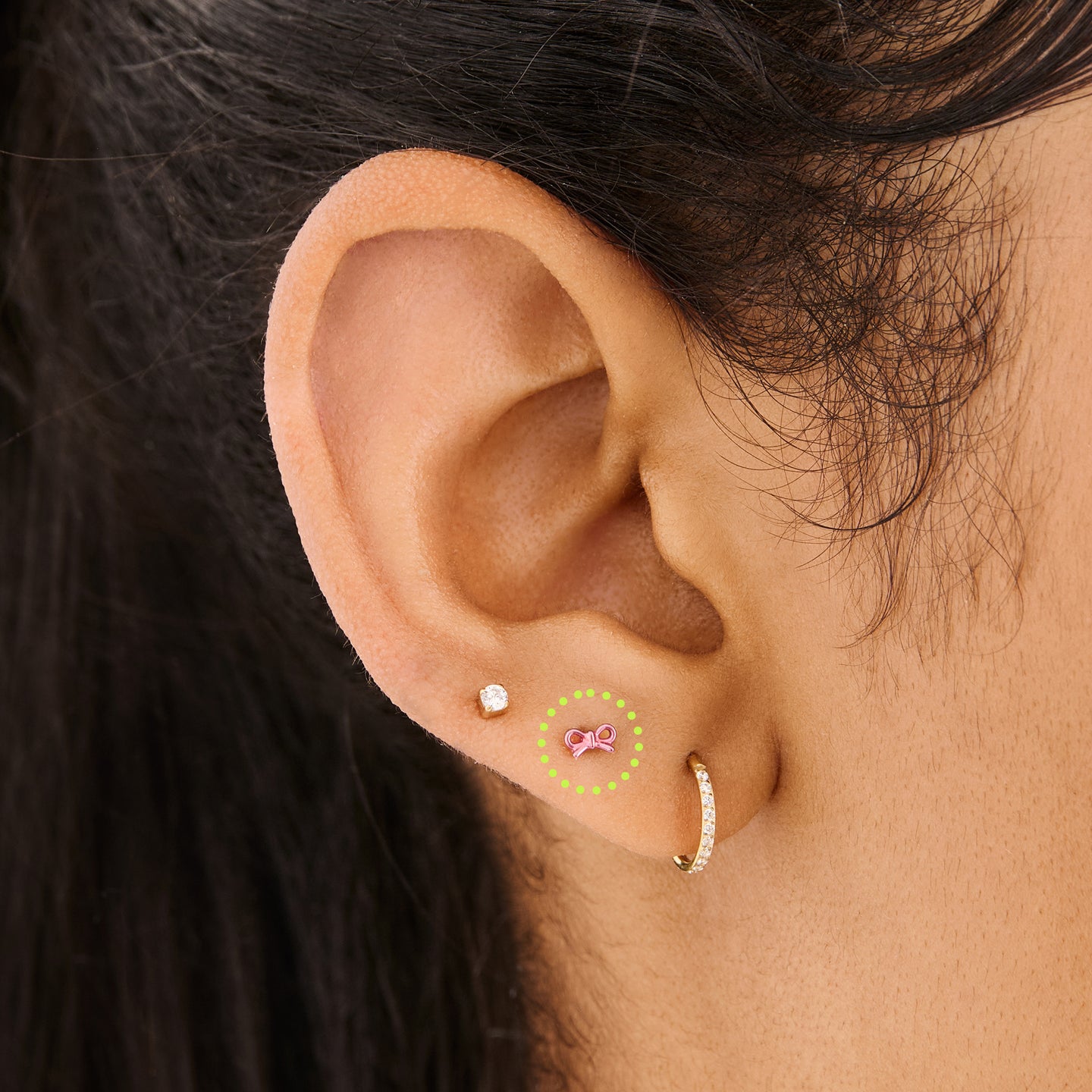 This image is of a pink bow-shaped flatback stud made out of titanium on ear. [hover] color:null|pink