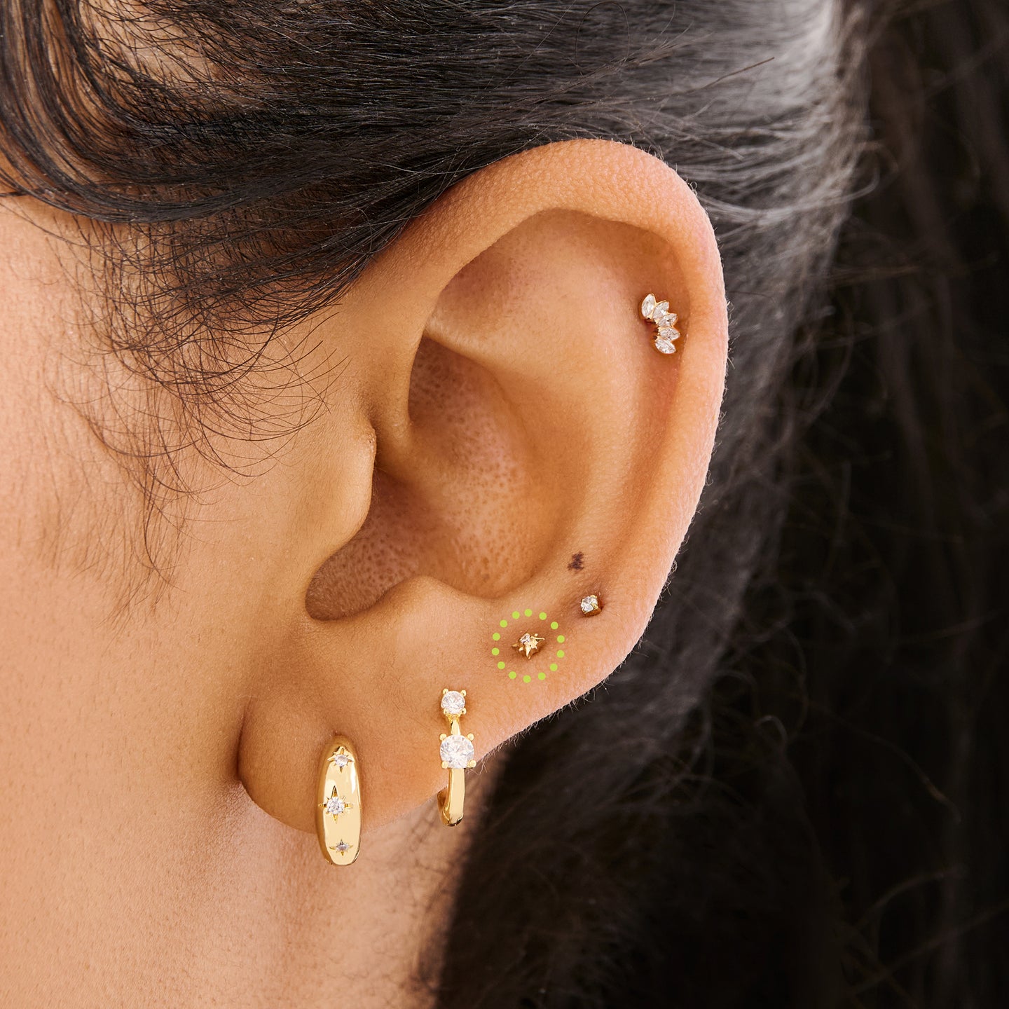 This is an image of a gold-toned flatback stud that is in the shape of a twinkle star with a clear CZ in the middle on ear. [hover] color:null|gold/clear