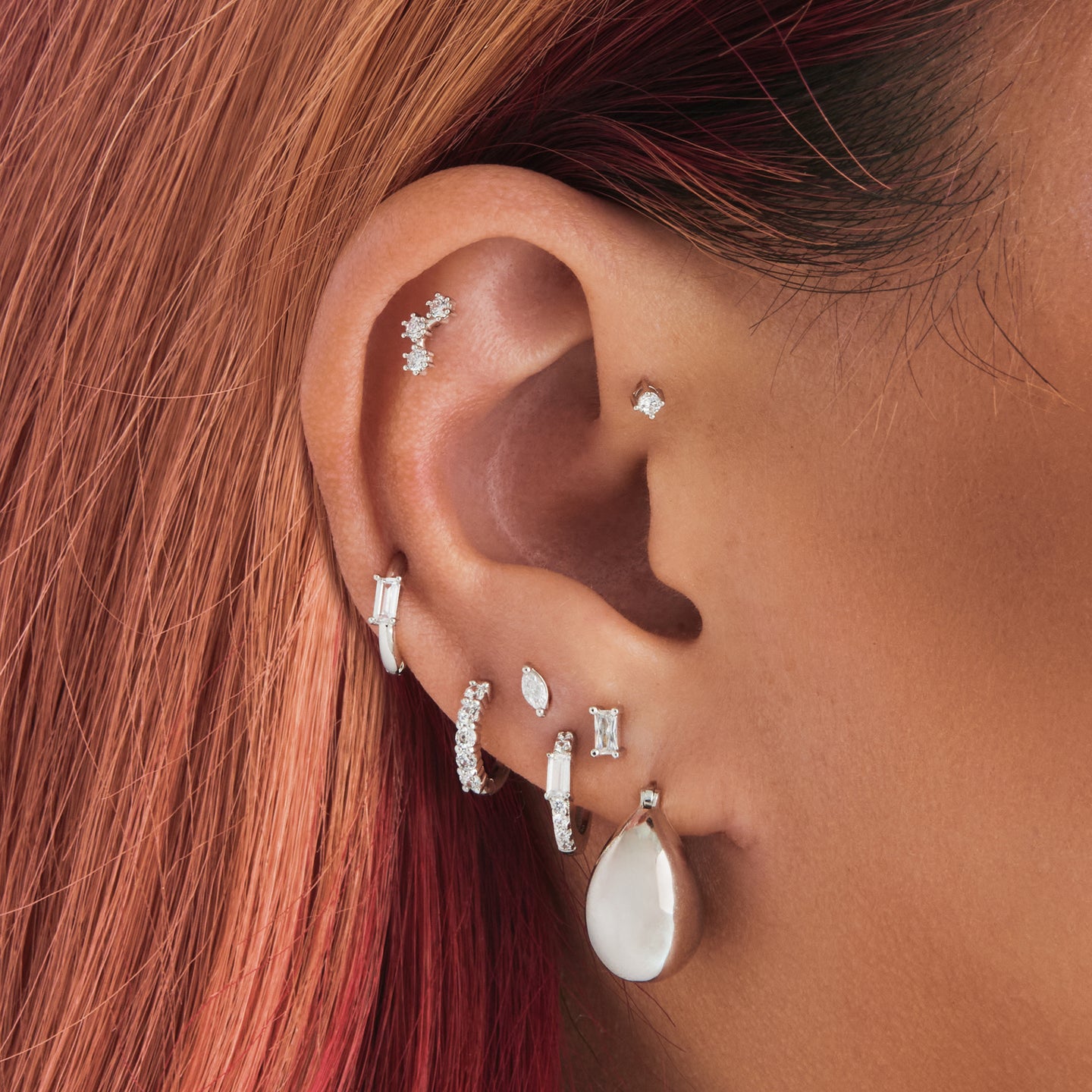 An image of a silver, small chunky crescent-shaped hoop on ear. [hover] color:null|silver