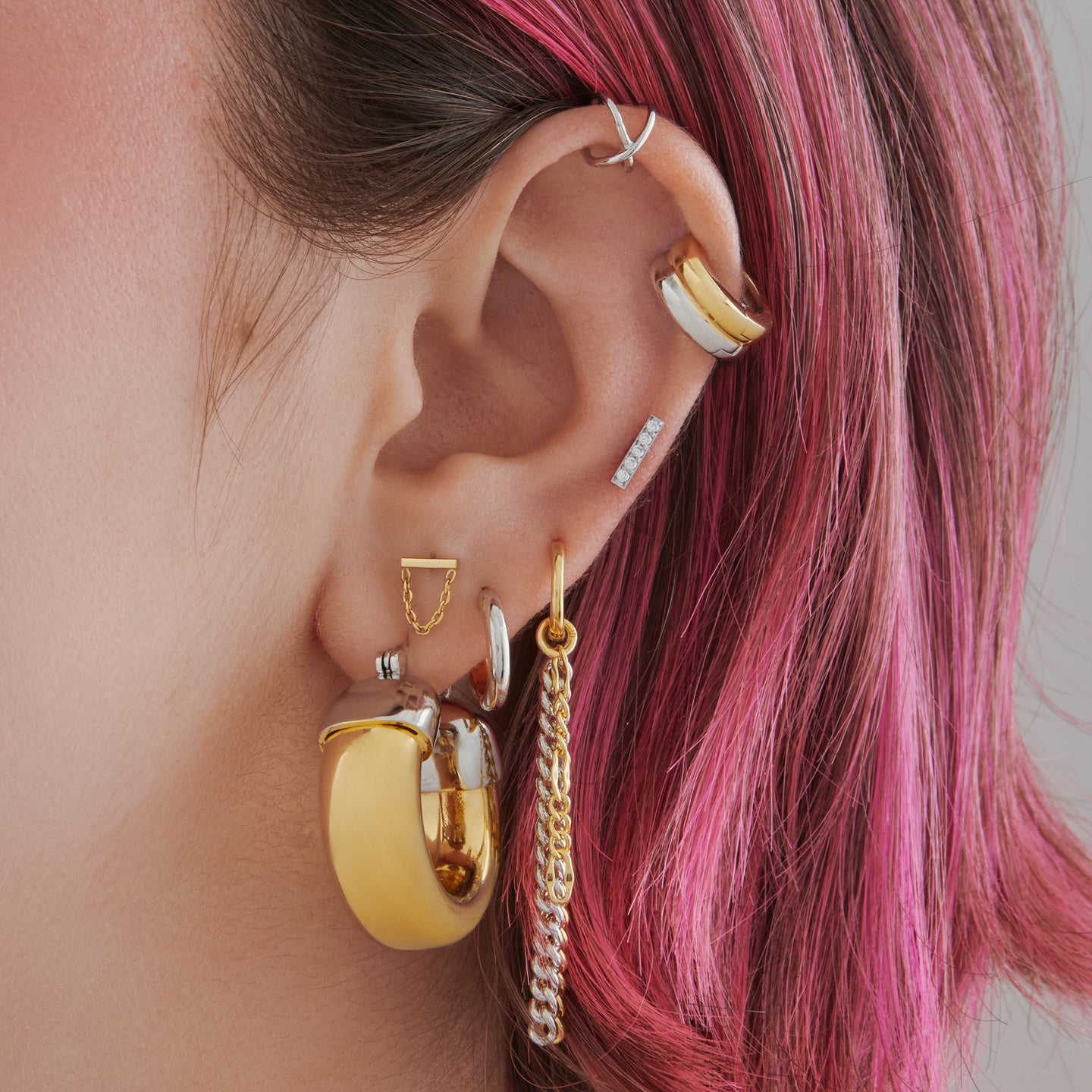 This is an image of a gold based, silver capped, chunky drip hoop on ear. [hover] color:null|gold/silver