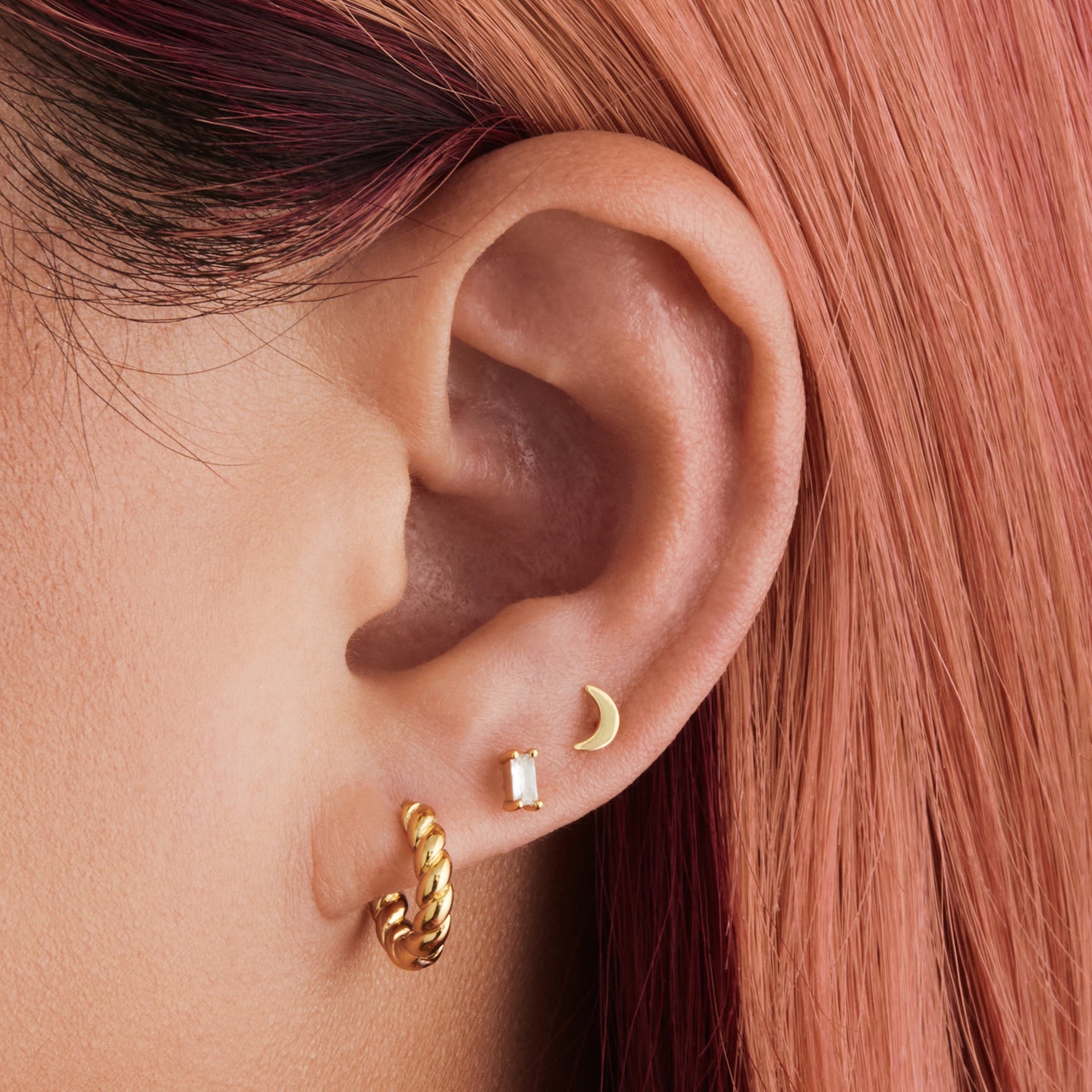 An image of a chunky gold twisted huggie on ear. [hover] color:null|gold