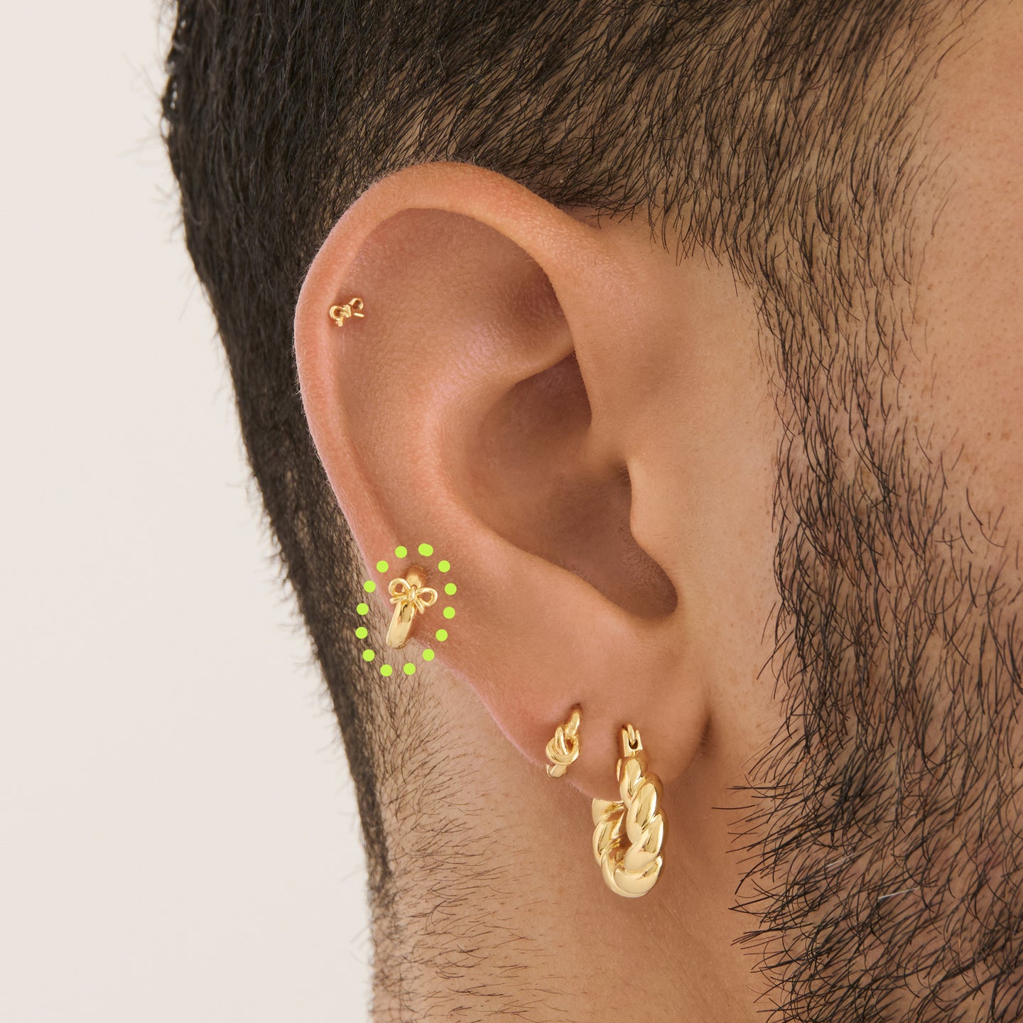 on ear featuring a micro huggie with a small bow accent in gold [hover] color:null|gold