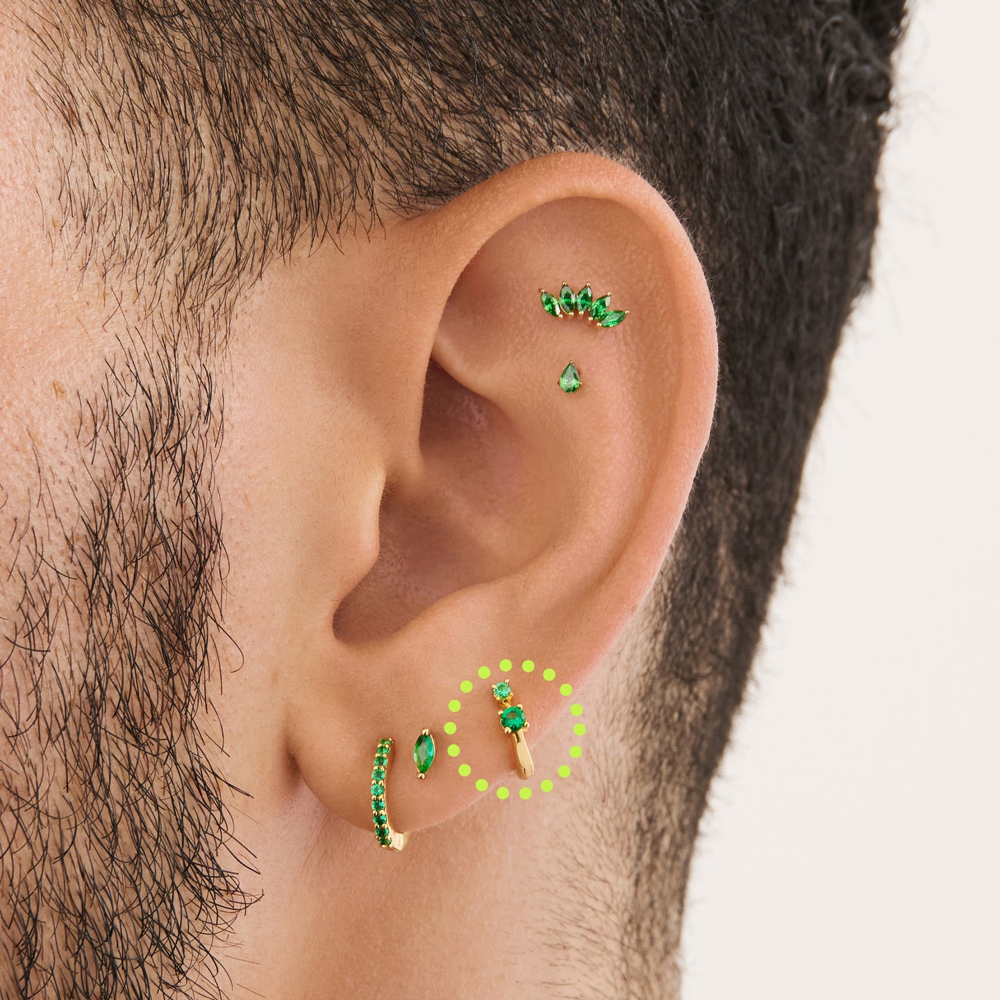 on ear featuring a micro huggie in gold with 2 mini green cz stones [hover] color:null|gold/green