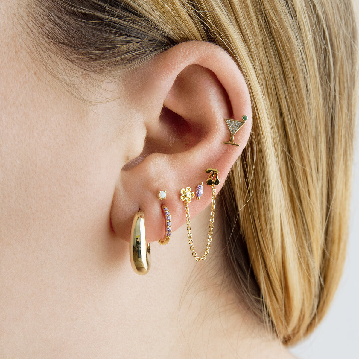 This image shows a 14k yellow gold pave martini flatback stud with a green cz stone on ear 