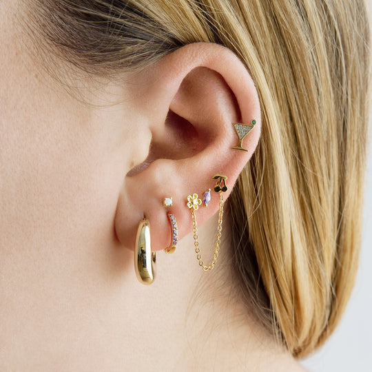 This image shows a 14k yellow gold pave martini flatback stud with a green cz stone on ear 