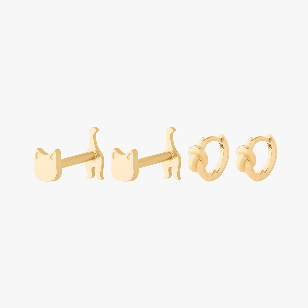 Gold earring set featuring a pair of reversible cat flatbacks and a pair of knot huggies 