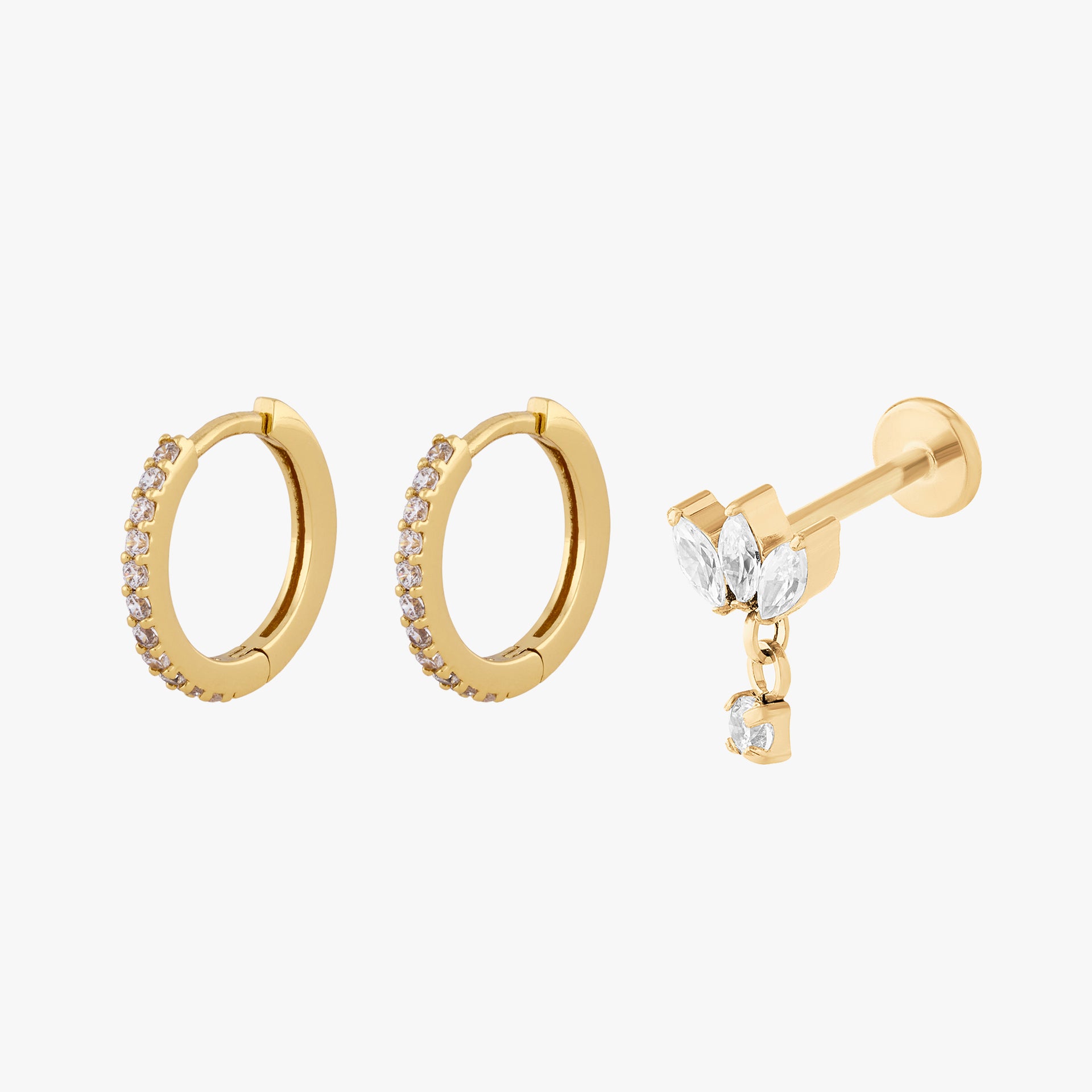 Set of gold hoop earrings and a gold stud earring with clear stones on a white background