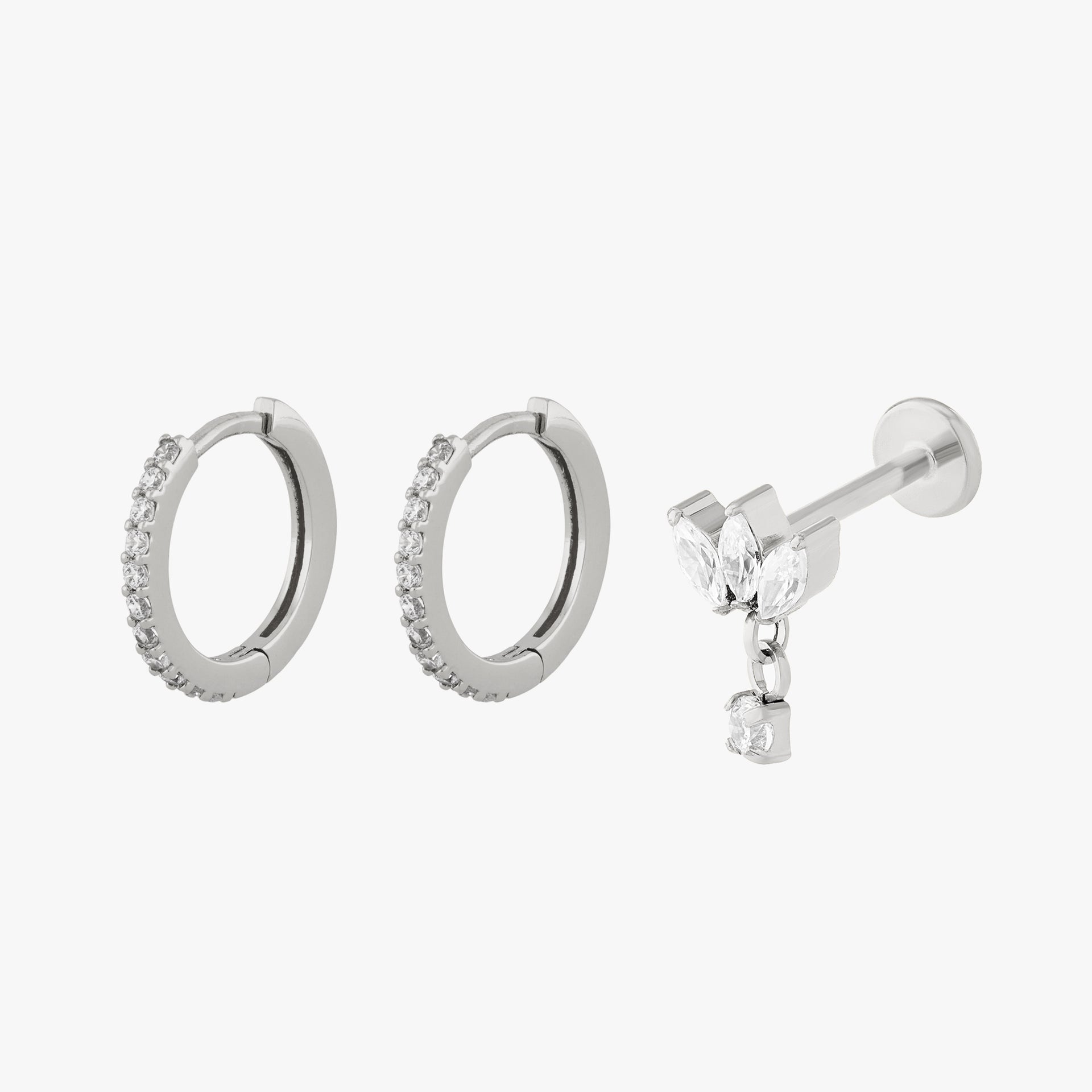 Set of silver hoop earrings and a silver stud earring with a small charm on a white background