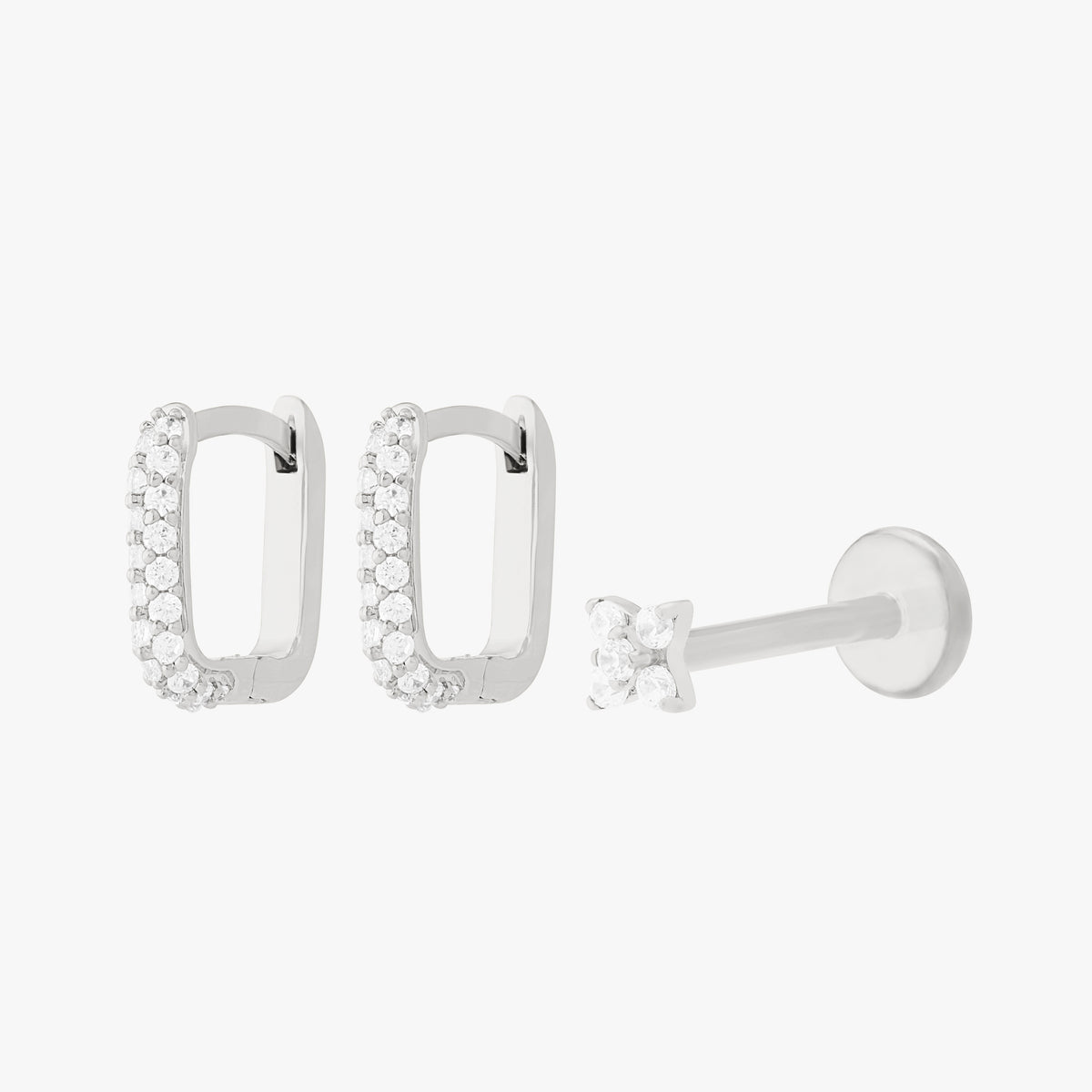 A silver earscape set featuring a pair of square pave huggies and a pave x flatback with clear stones