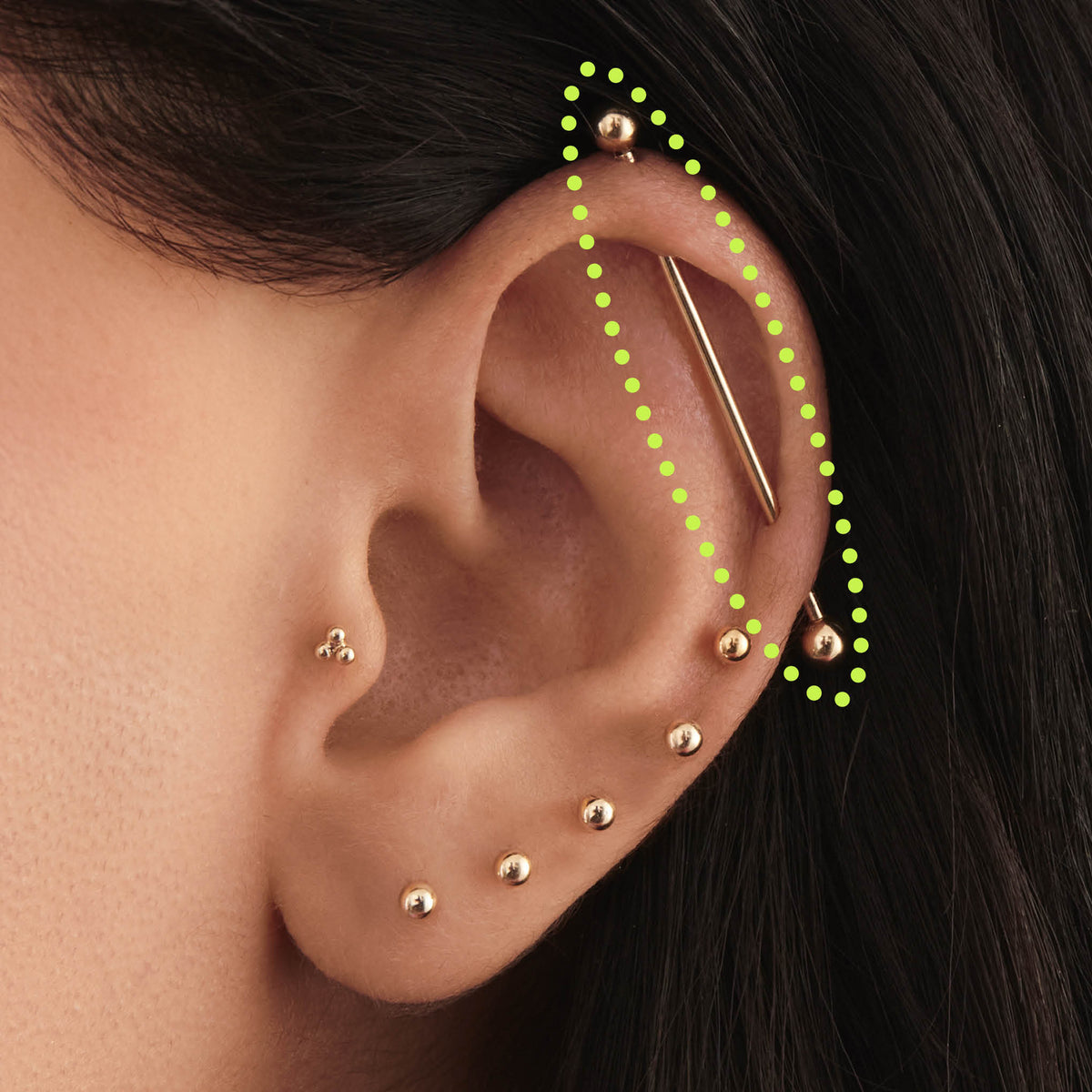 This is an image of a 14K gold industrial bar that is 38mm in length circled on an ear. 
