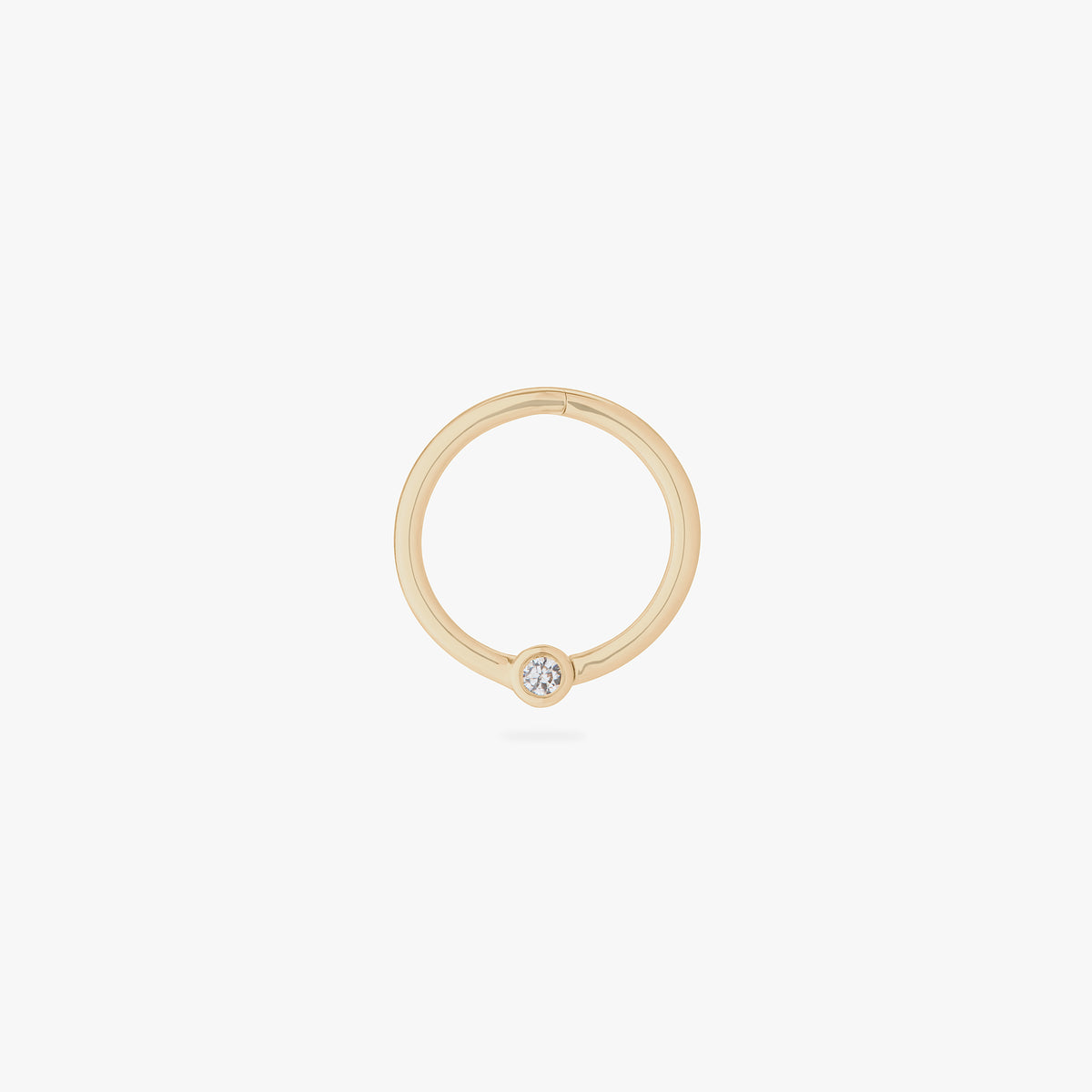 This is an image of a 14K gold clicker that is 10mm wide with a bezel set crystal CZ against a white background.