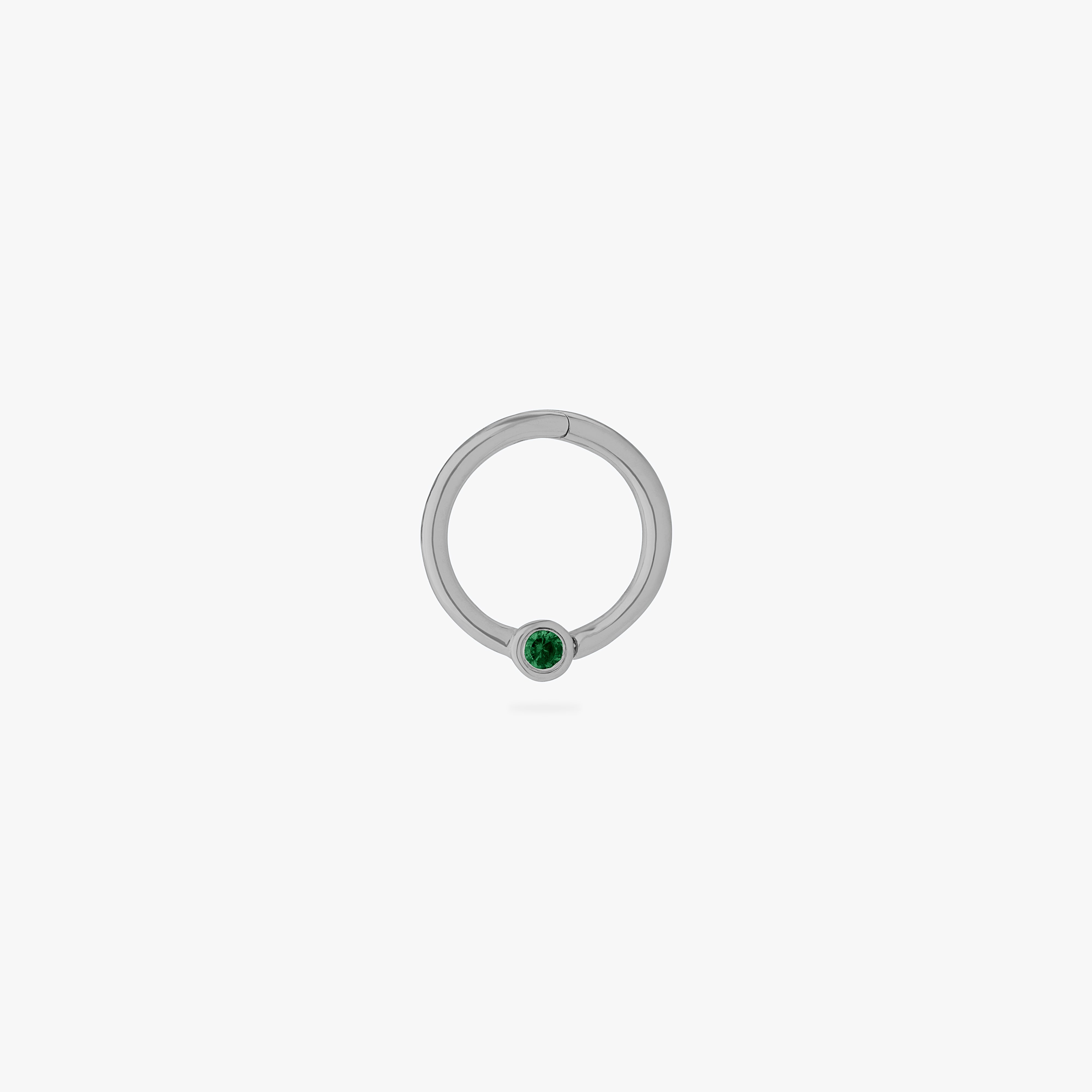 This is an image of a silver-toned titanium clicker that is 8mm wide with a bezel set green CZ against a white background. - Main view