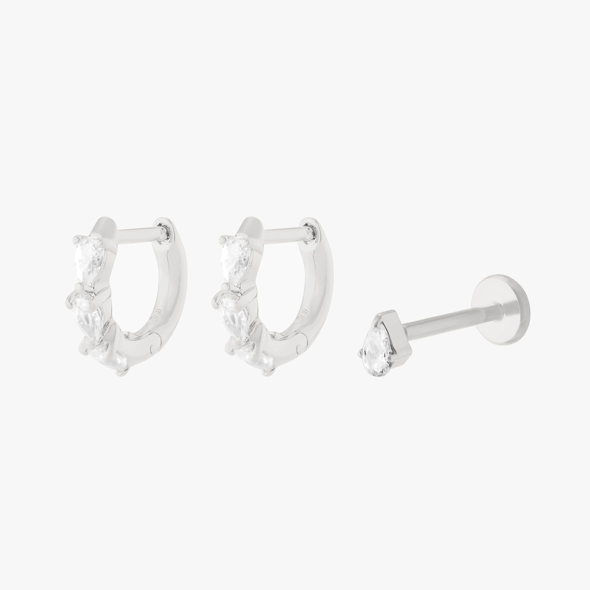 Silver huggie earrings and a silver stud earring on a white background