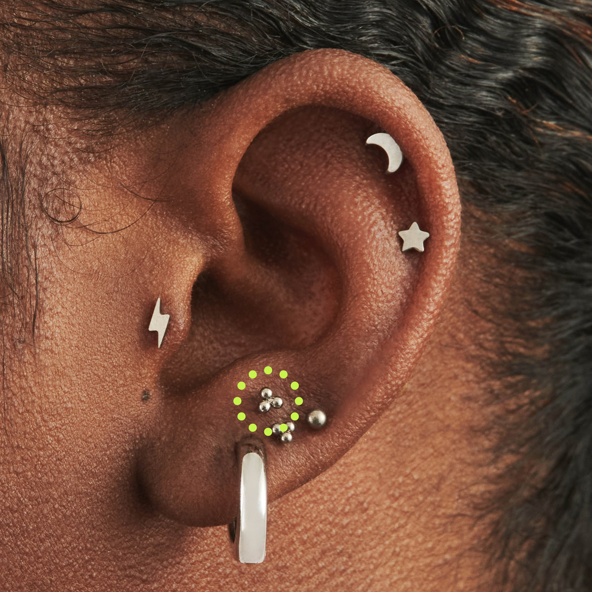 This image is a silver toned titanium ball-shaped flatback stud circled on an ear.