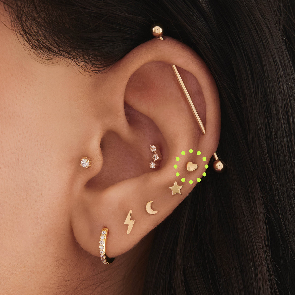This is an image of a 14k gold flatback stud in the shape of a heart on ear. 