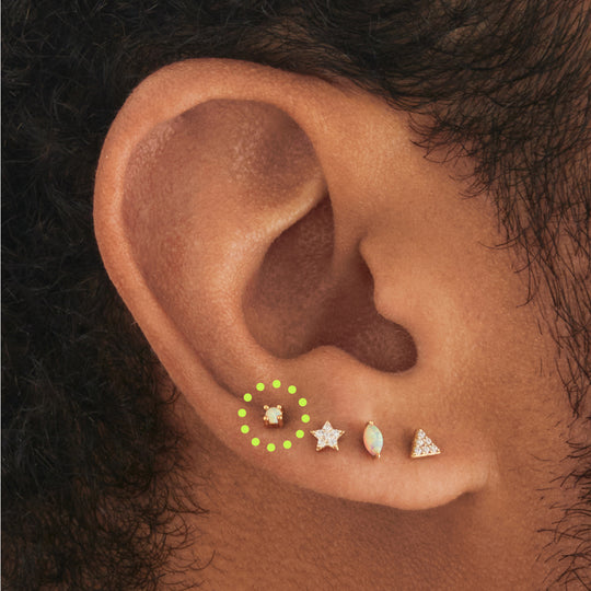 This image is a 14K gold flatback stud with a mini opal circled on an ear.