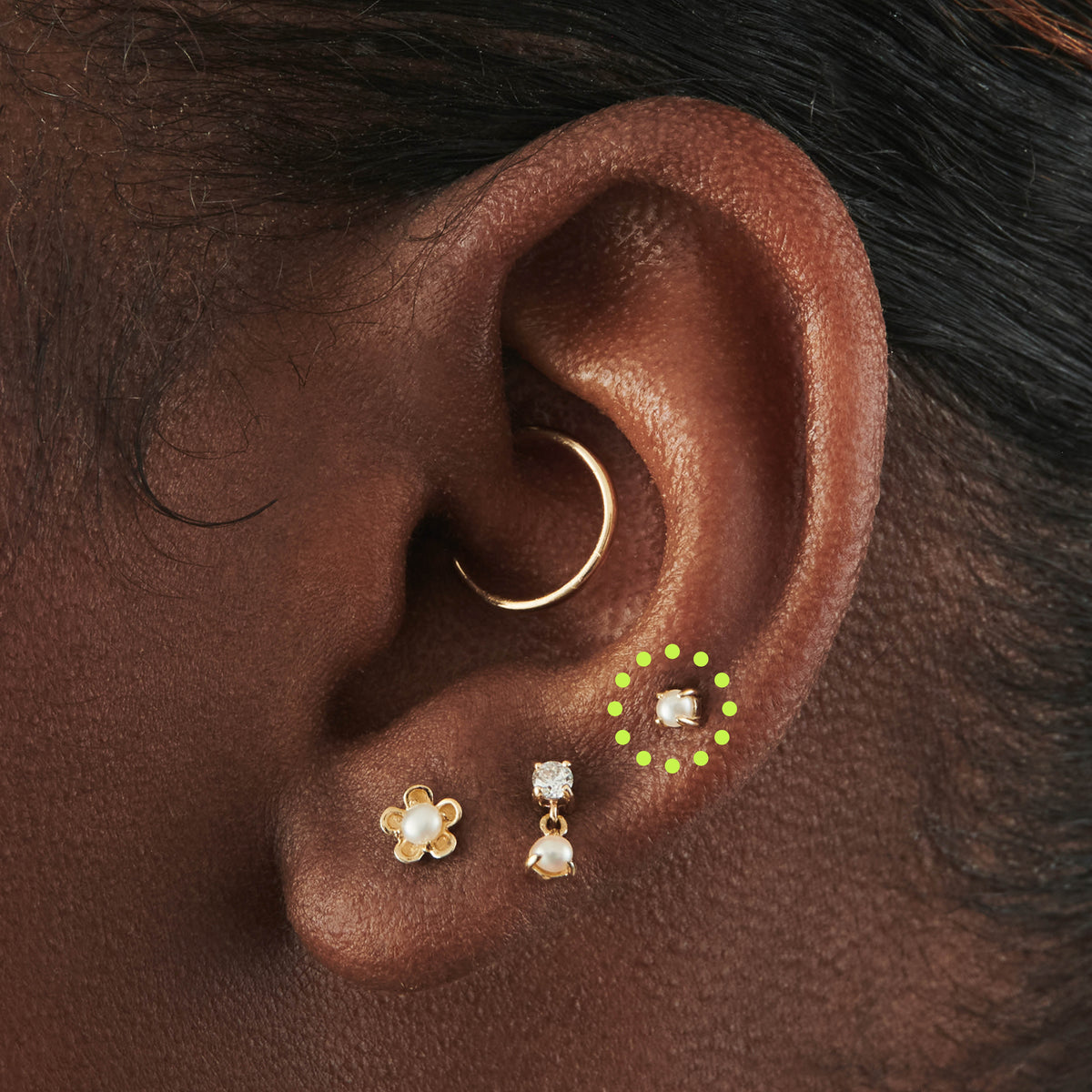 This image is a 14K gold flatback stud with a mini pearl circled on an ear.