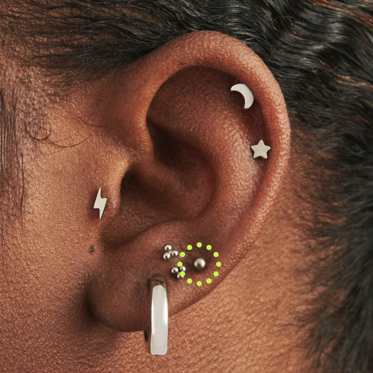 This image is a silver toned titanium ball-shaped flatback stud circled on an ear.