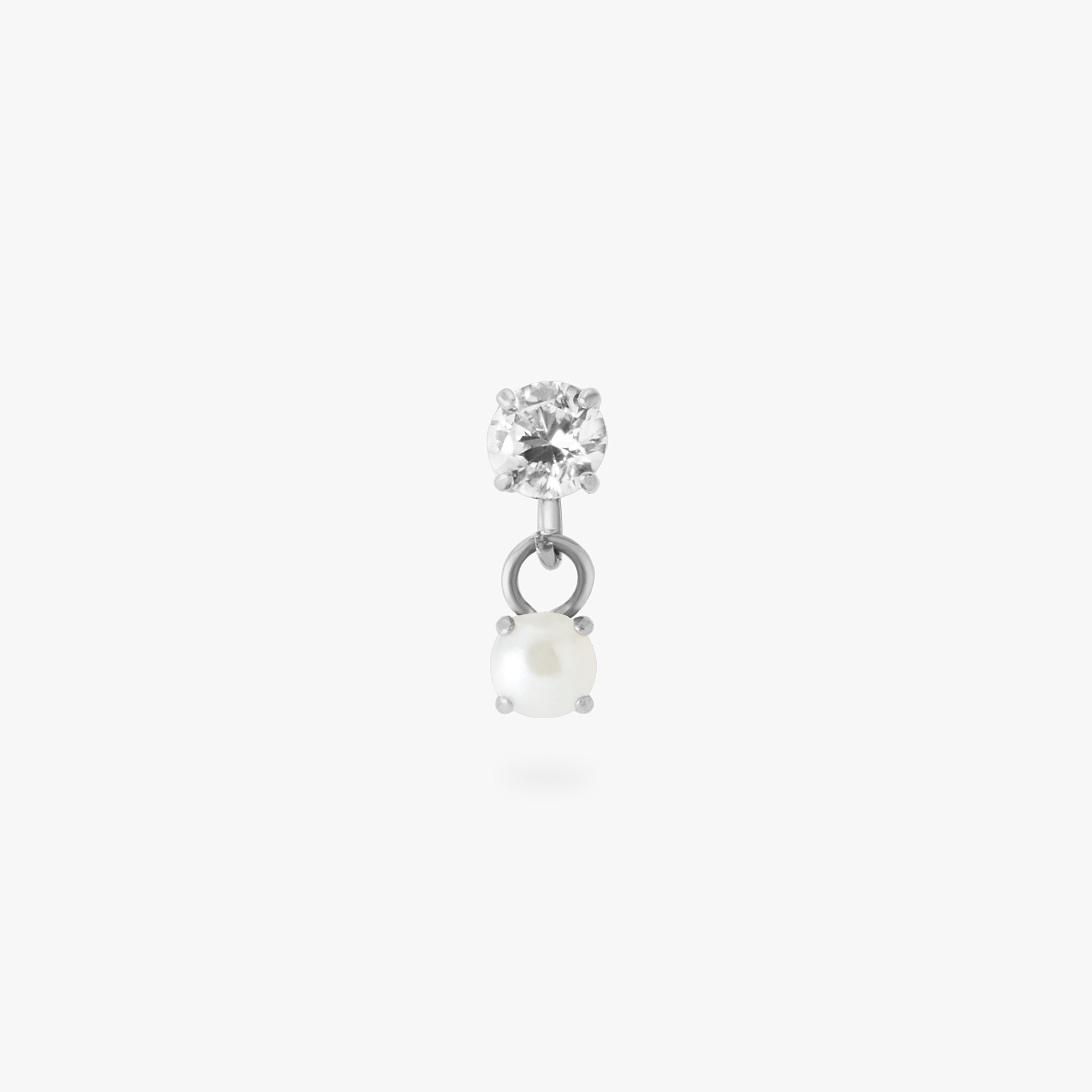 This image is a silver toned titanium flatback stud that features a larger crystal CZ stone with a smaller pearl stone dangling from it against a white background. - Main view
