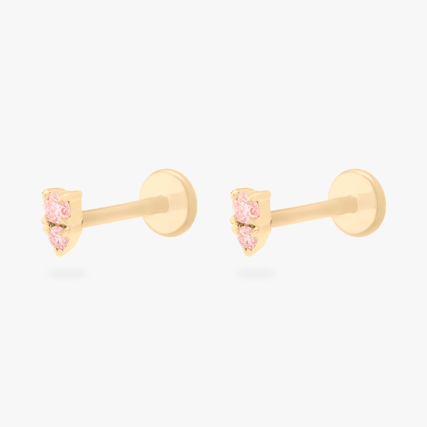 This image shows a pair of flatback studs made of 14K gold with round pink diamond stones that are stacked over small triangular pink diamond stones with their gold-toned labret backs on. [pair] color:null|pink|gold/pink