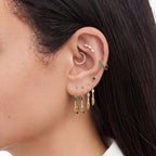 This is an image of an ear displaying the pave pear safety pin earring in 4 different colors on ear--In gold/green, gold/blue, gold/pink, and gold/clear color ways.