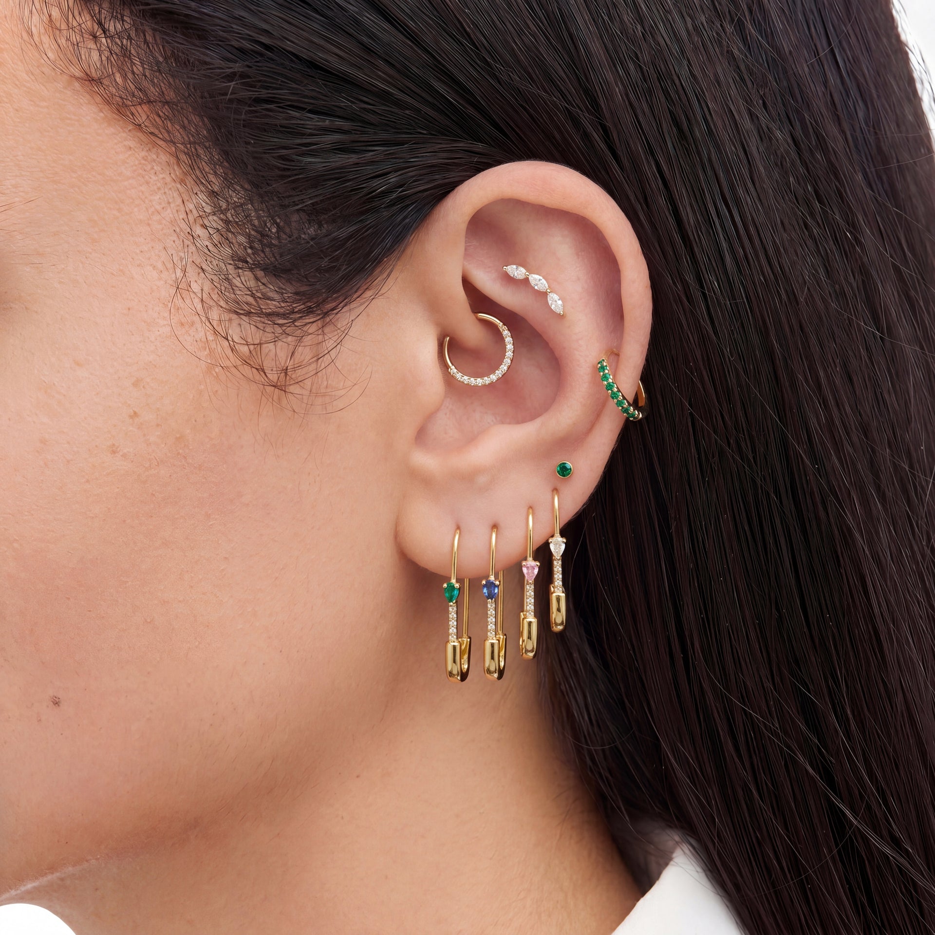 This is an image of an ear displaying the pave pear safety pin earring in 4 different colors on ear--In gold/green, gold/blue, gold/pink, and gold/clear color ways. - Alternative view 1