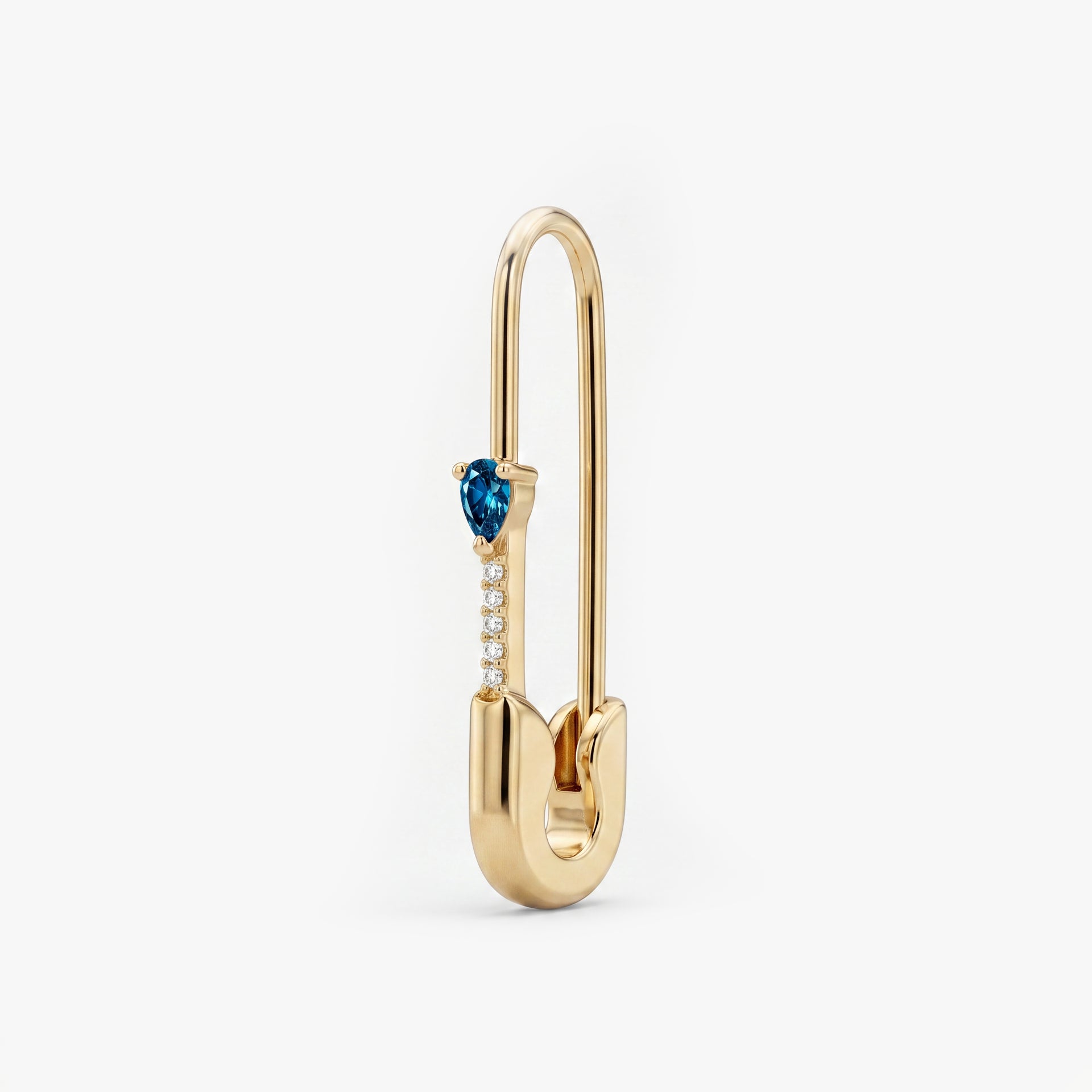 This is an image of a 14k yellow gold plated brass earring shaped like a safety pin with a blue pear cut CZ stone and 5 clear accent stones below the pear CZ. - Main view