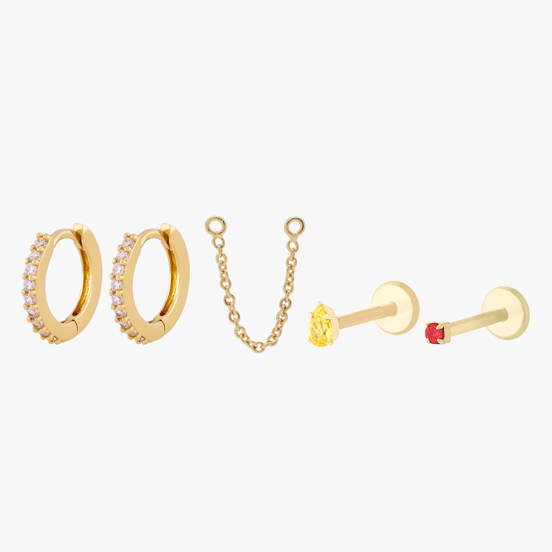 This image shows a set of two pave huggies with a connector chain, a 14k yellow gold Pear flatback with a cz topaz stone and a 14k Gold plated micro cz flatback stud with a garnet cz stone.