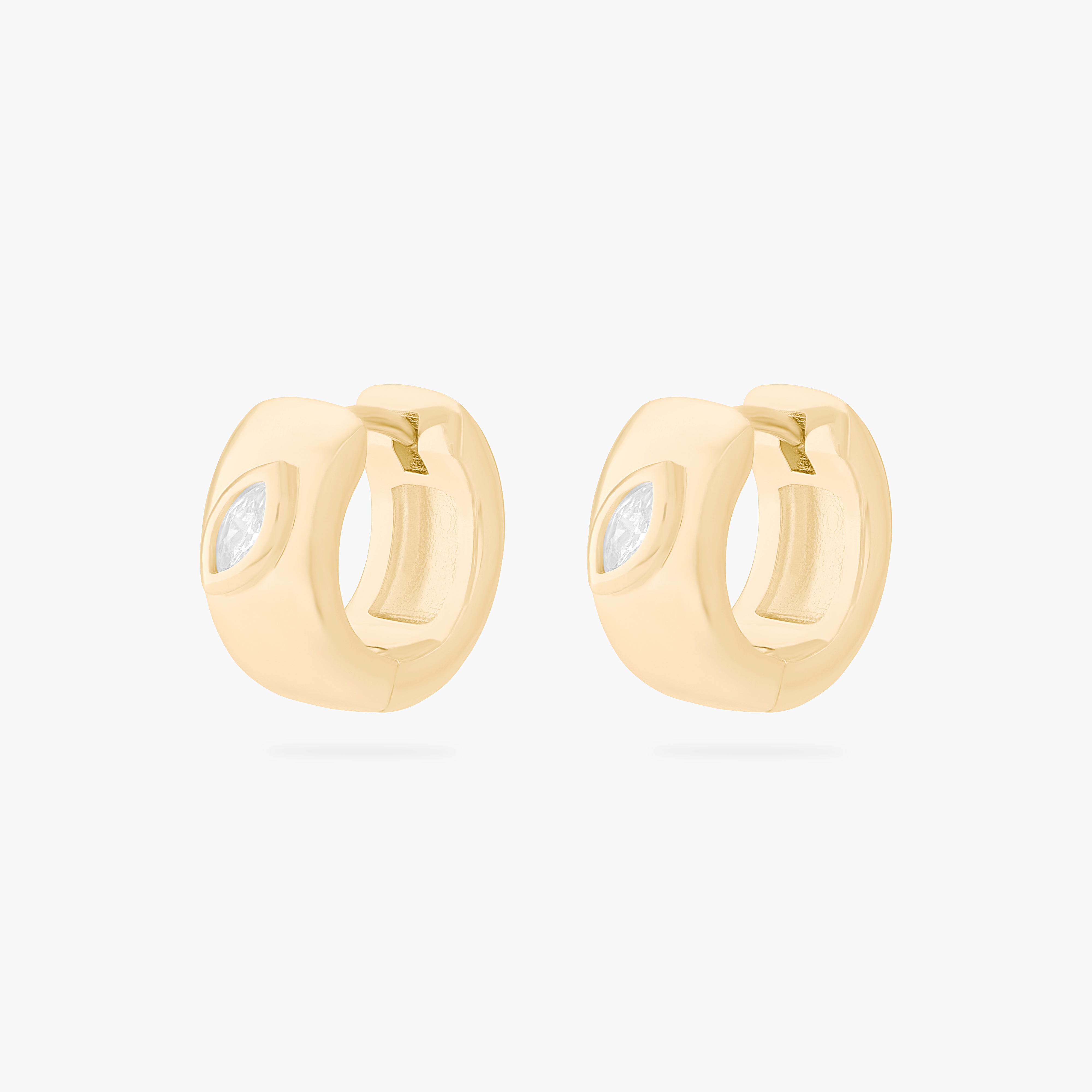 This is an image of a pair of gold toned huggies that are chunky and have marquise shaped cz's in it. [pair] color:null|gold/clear