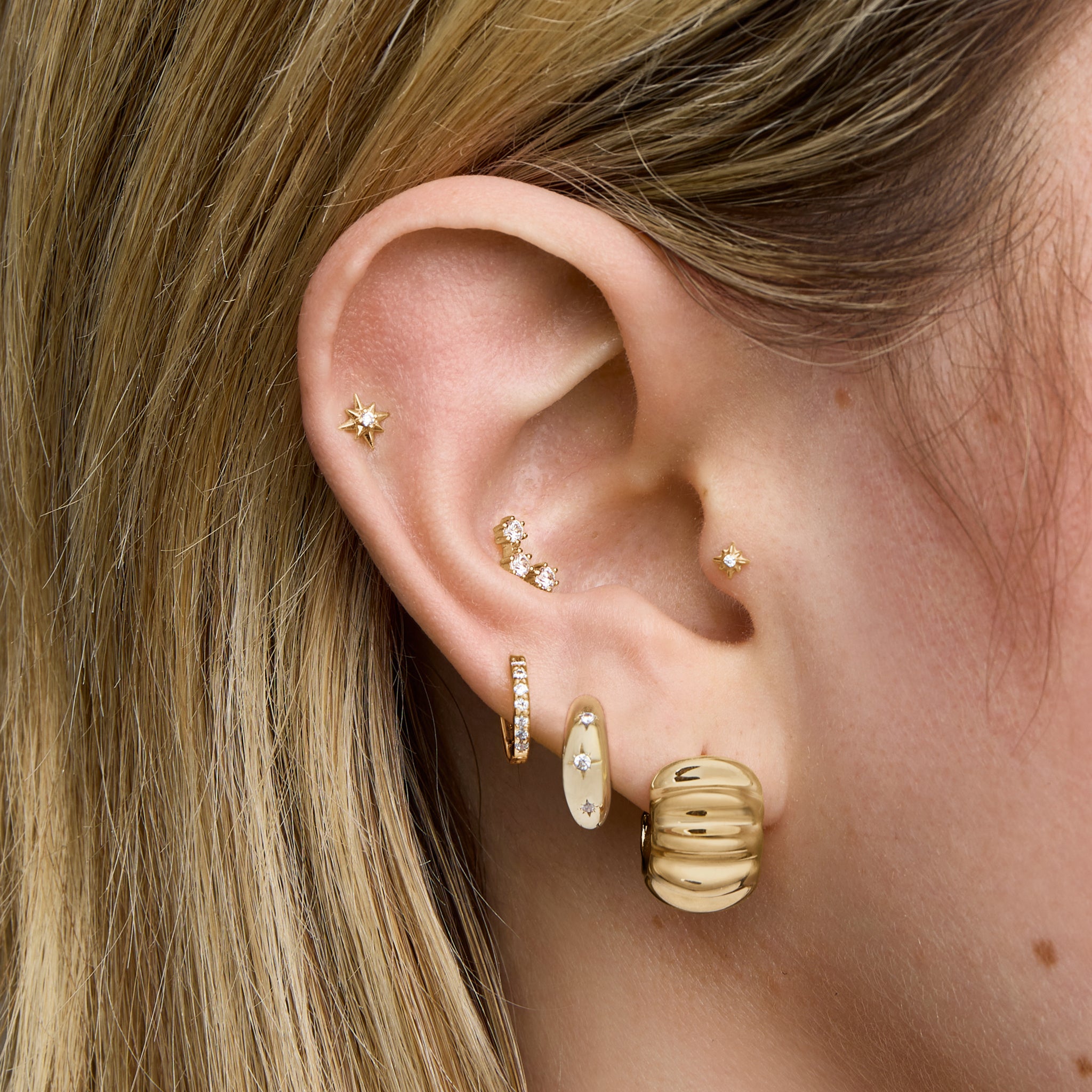 This is an image of a gold toned butterfly back earring that has a ridged detailing along the edge. [hover] color:null|gold