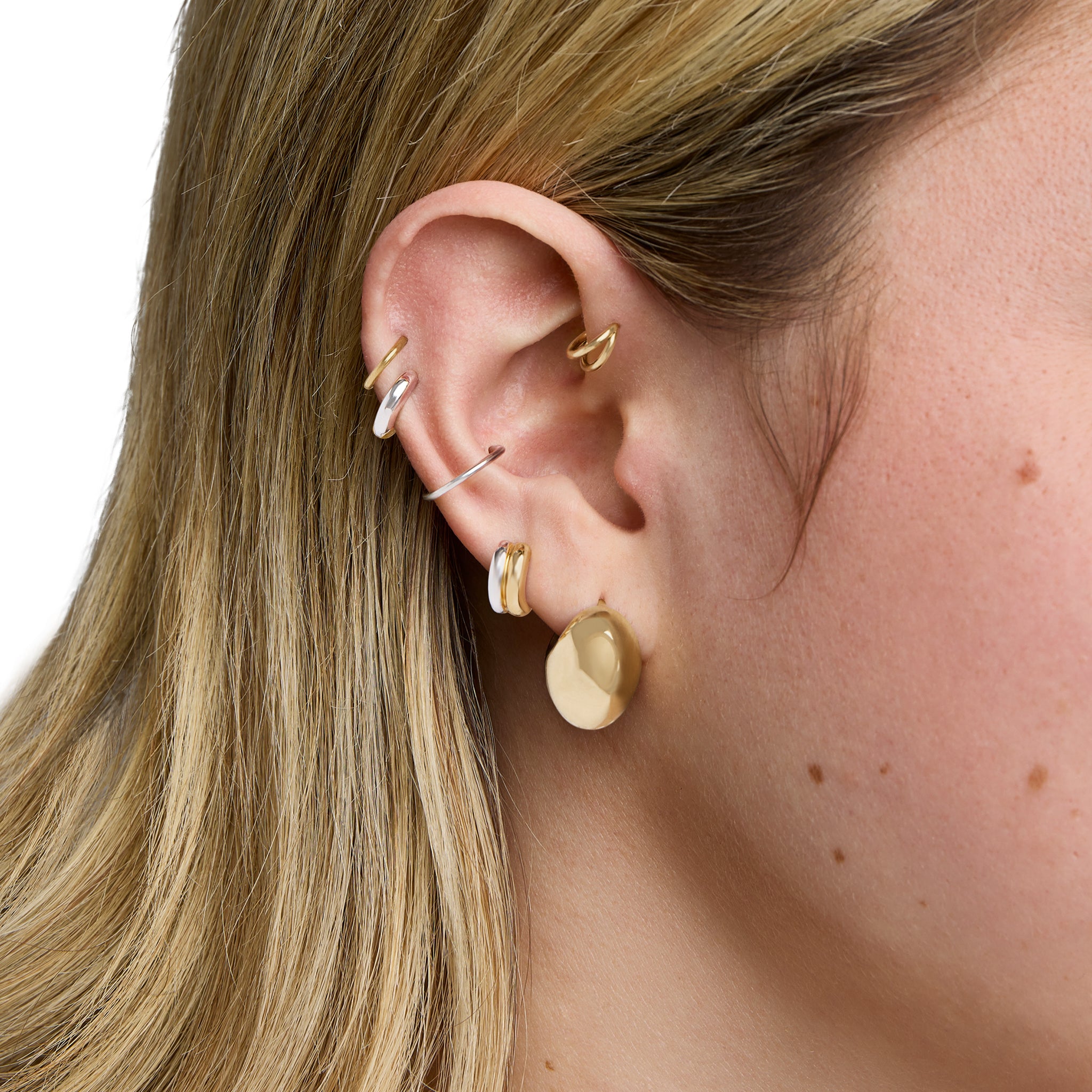 This is an image of a two-toned gold and silver huggie that is chunky and crescent shaped. color:null|gold/silver