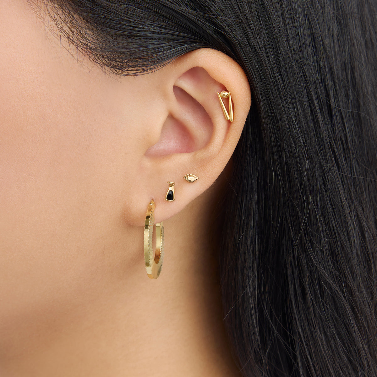 This is an image of a 14K gold plated hoop that has a fluted, shell-like finish on an ear.