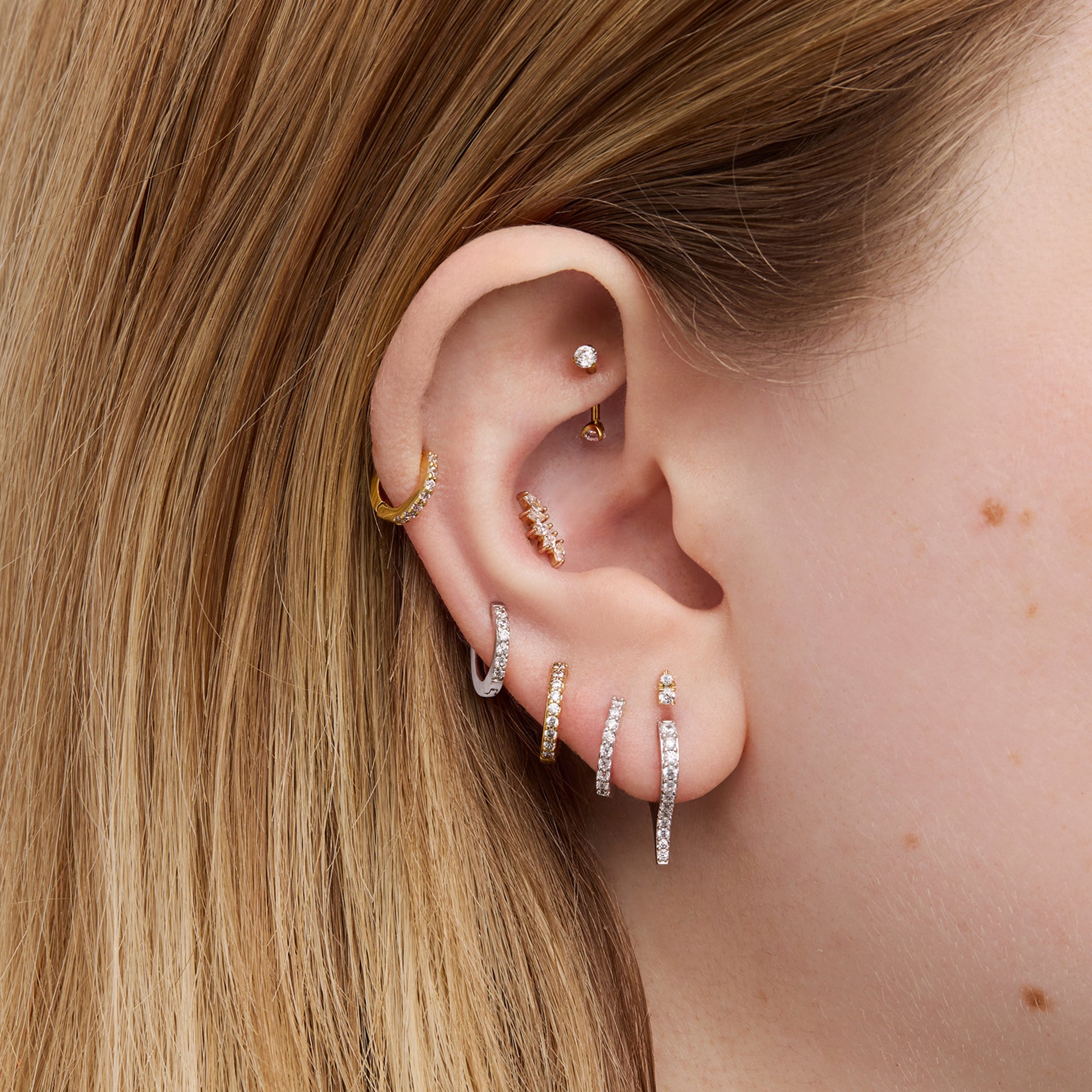 Close-up of an ear with multiple earrings.