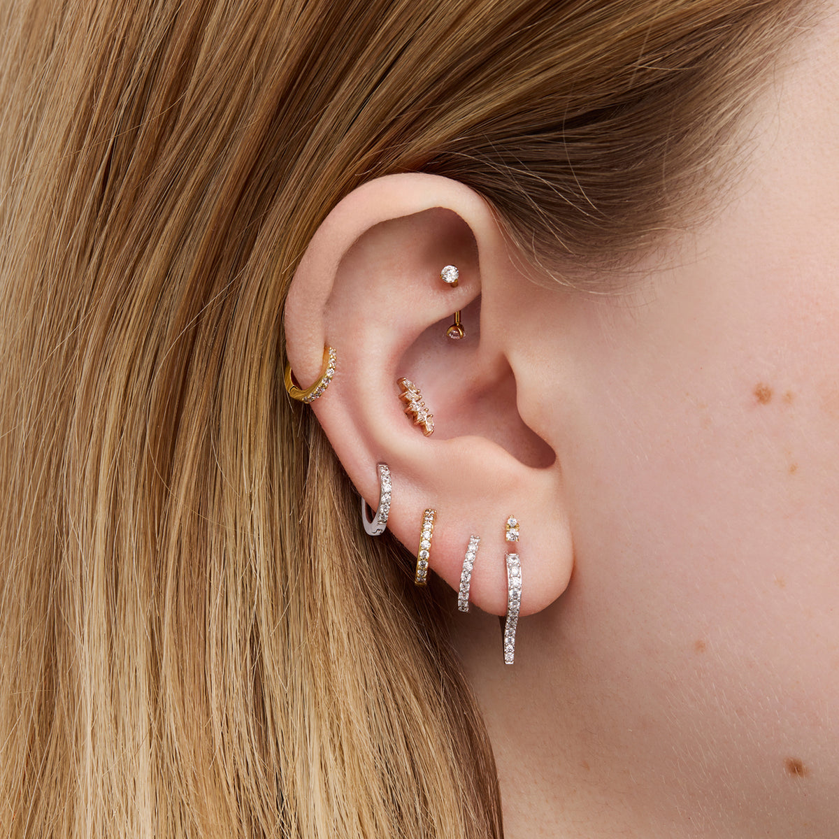 Close-up of an ear with multiple earrings.