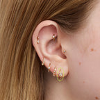Close-up of an ear with multiple gold and diamond earrings.