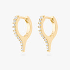 Pair of gold huggies with a spike and small clear stones on a white background