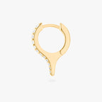 Gold huggie with a spike and small clear stones on a white background, side view